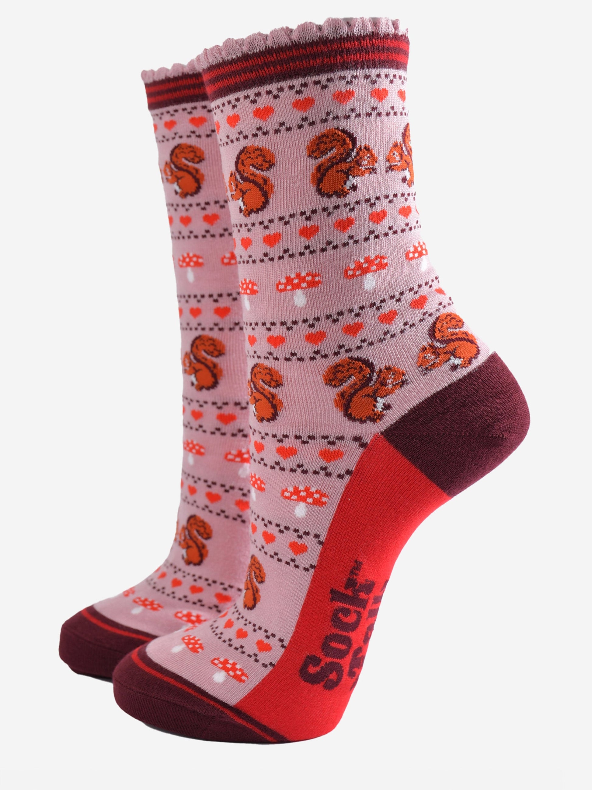 pink socks with a fair isle style pattern featuring toadstools, red love hearts and squirrels