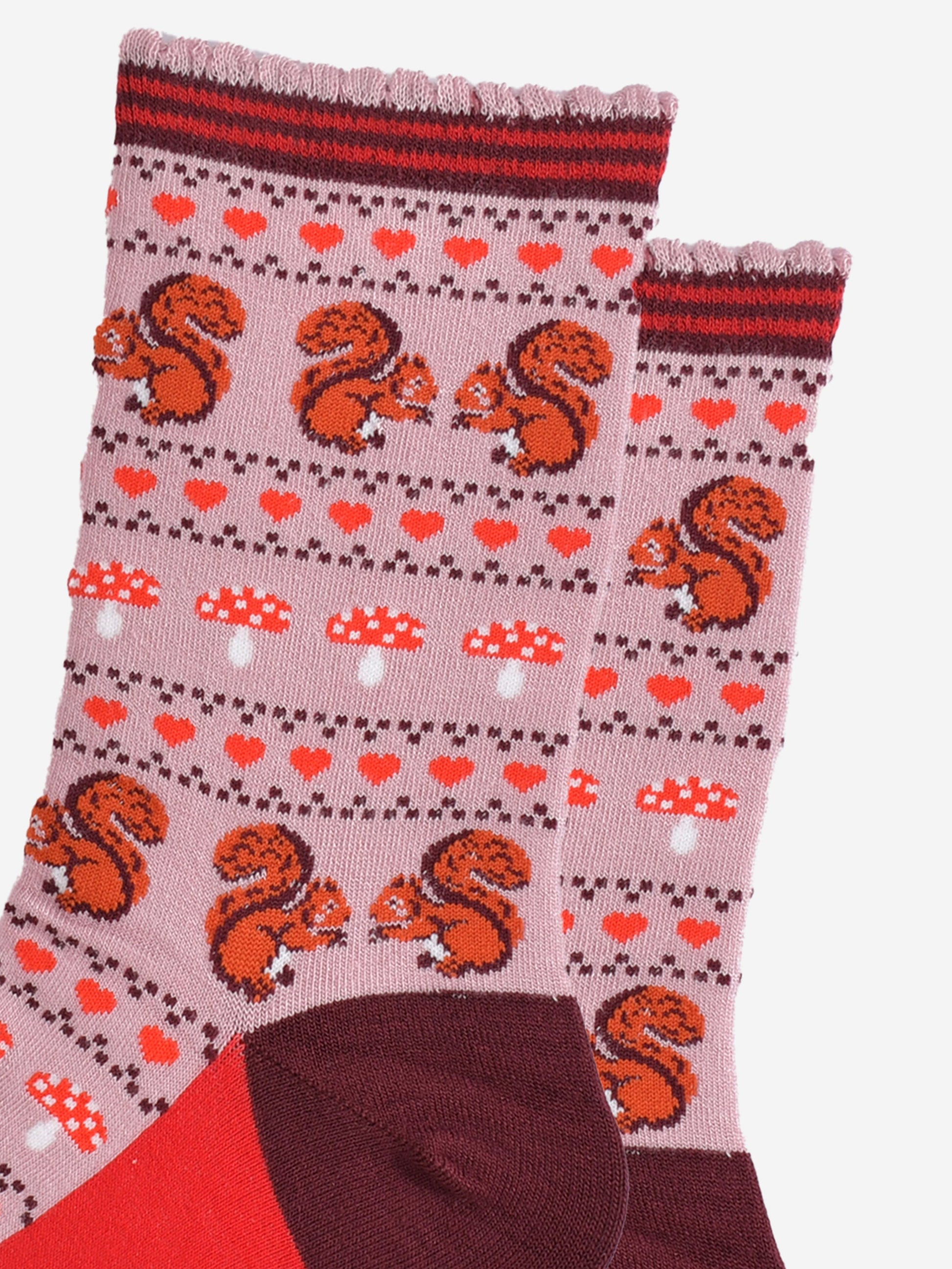 close up of the red squirrels, red love hearts and red toadstool fair isle pattern on the pink bamboo socks