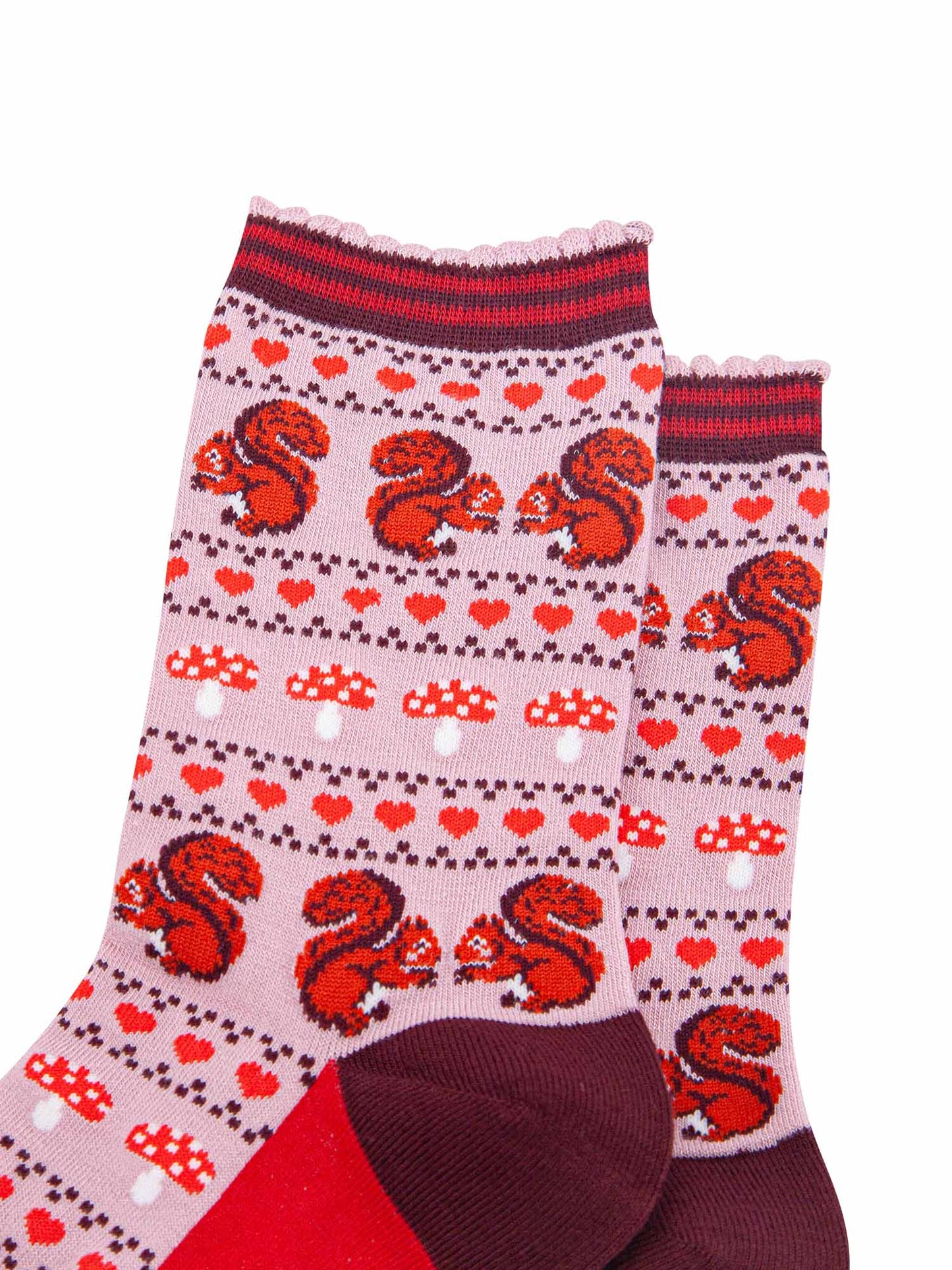 close up of the red squirrels, red love hearts and red toadstool fair isle pattern on the pink bamboo socks