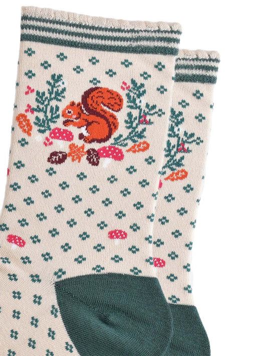 close up of the red squirrel and autumn foliage design on the ankle of the socks, the squirrel is holding an acorn and posed like it is foraging, it is surrounded by autumn leaves and pink toadstools
