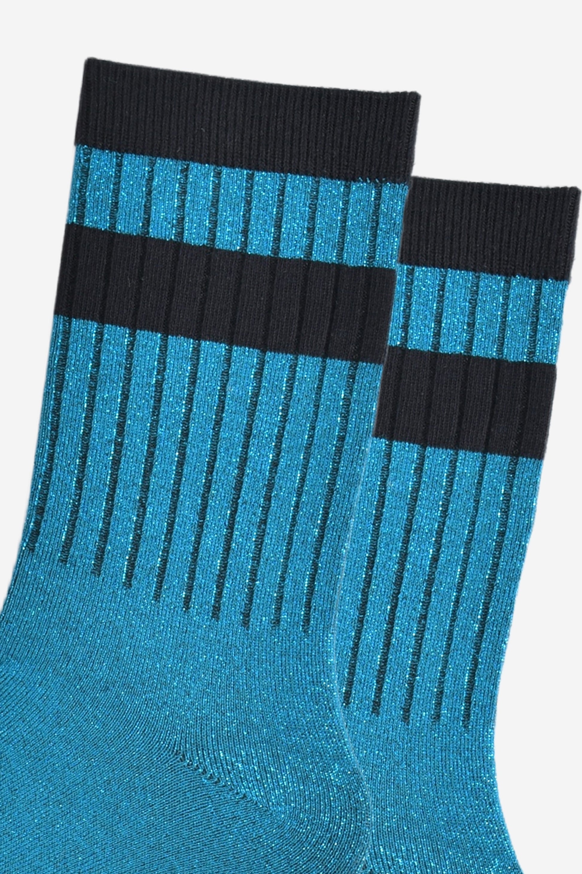 close up of the ribbed sports style cuffs on the socks. they have vertical ribbed details. the base of the socks are teal blue with a silver glitter sparkle. the cuff is black and there is a horizontal black band stripe, without glitter an inch below the cuff. 