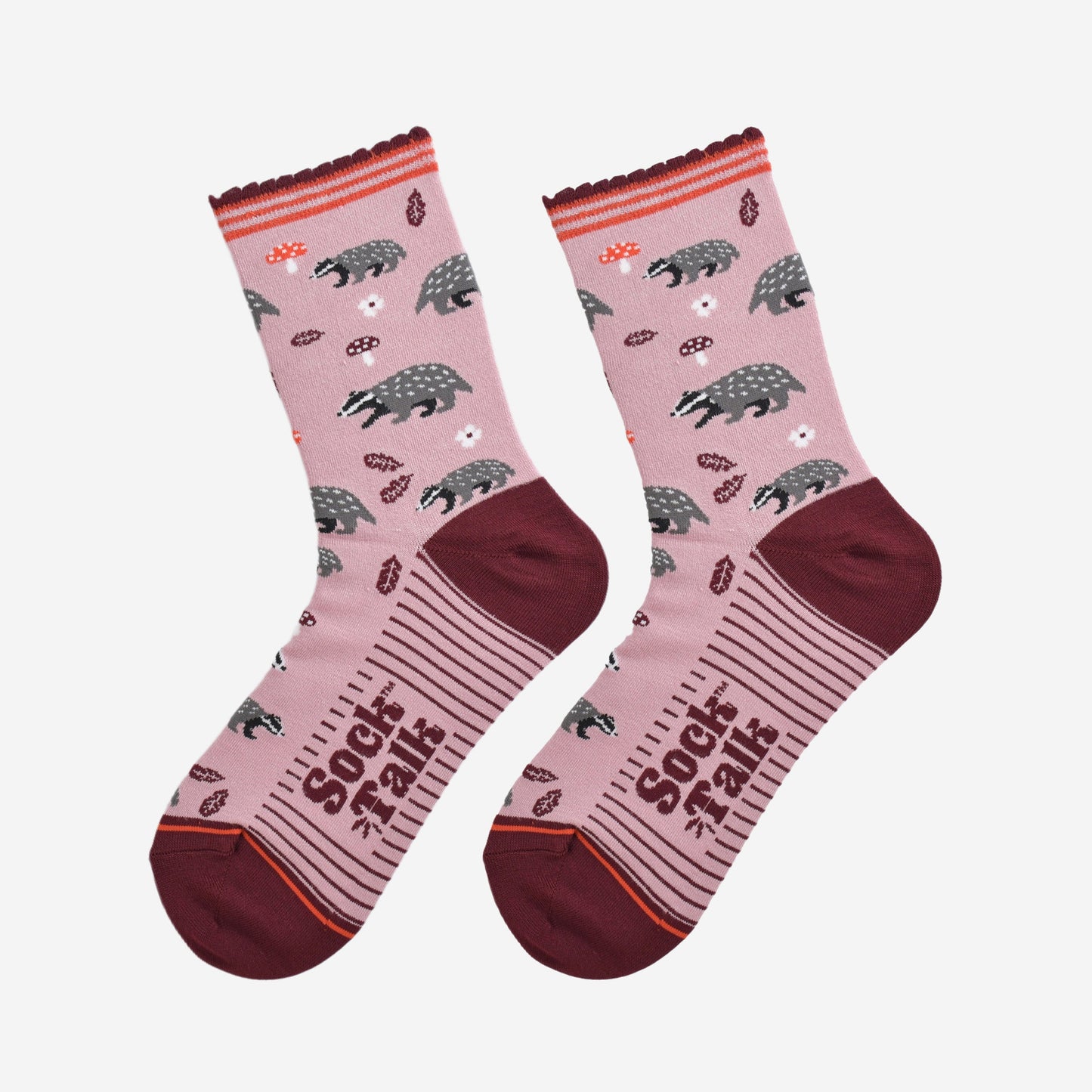 woodland badger bamboo socks laying flat, showing the pattern of badgers, toadstools and autumn leaves on a pink sock with burgundy accents