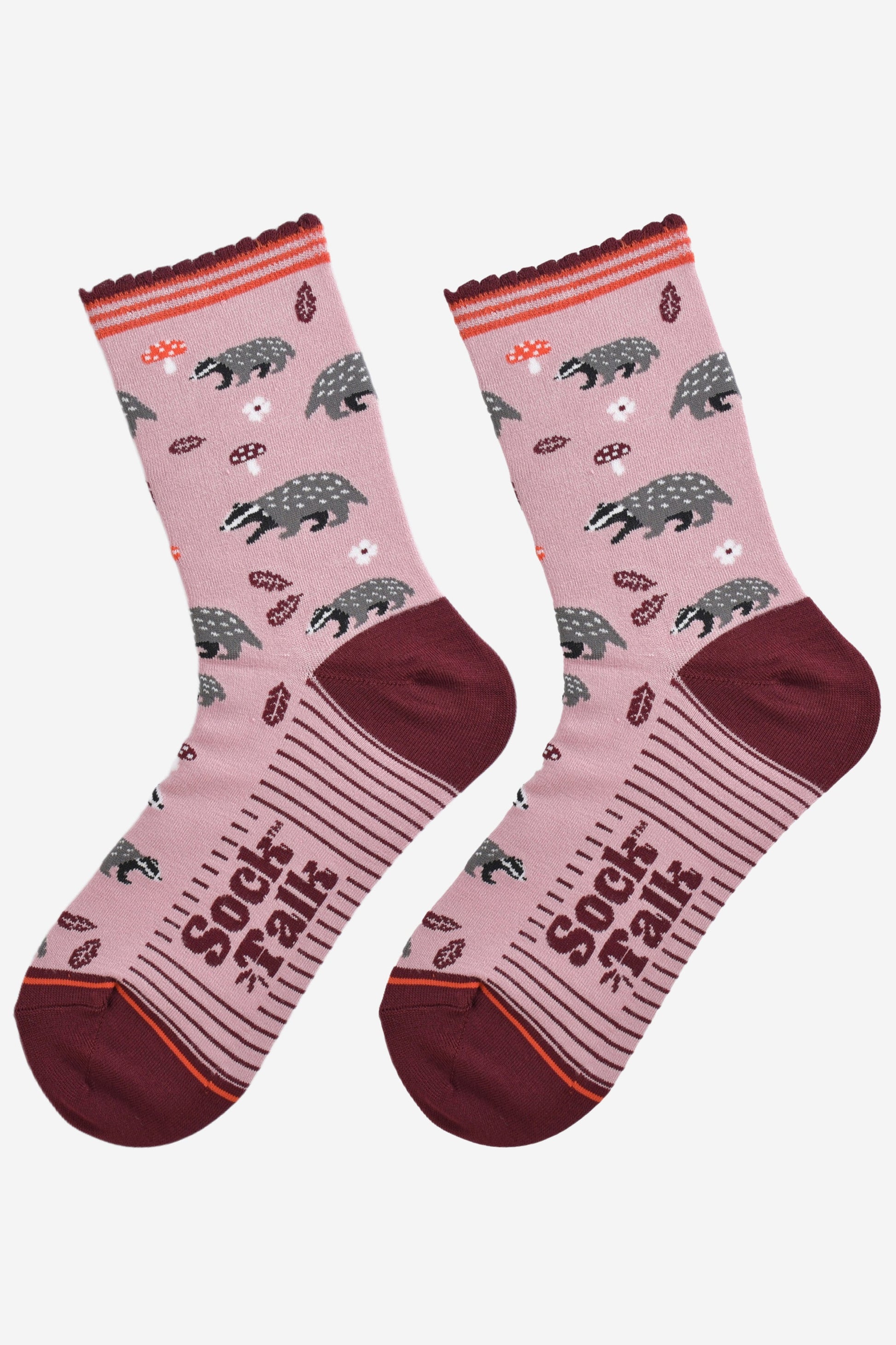 woodland badger bamboo socks laying flat, showing the pattern of badgers, toadstools and autumn leaves on a pink sock with burgundy accents