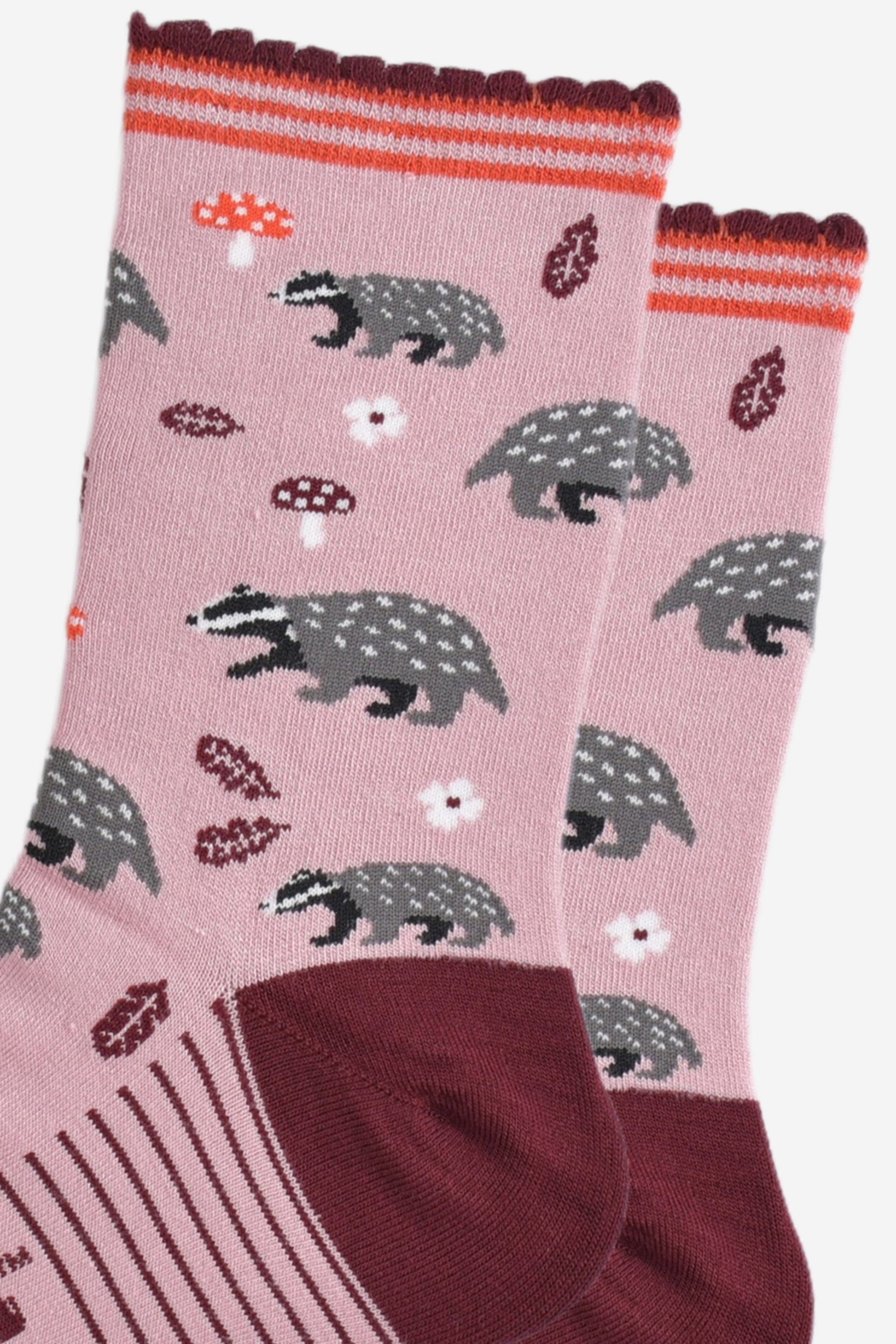 close up of the woodland badger pattern, the socks have grey and black badgers, red toadstools, burgundy red leaves and white flowers on them