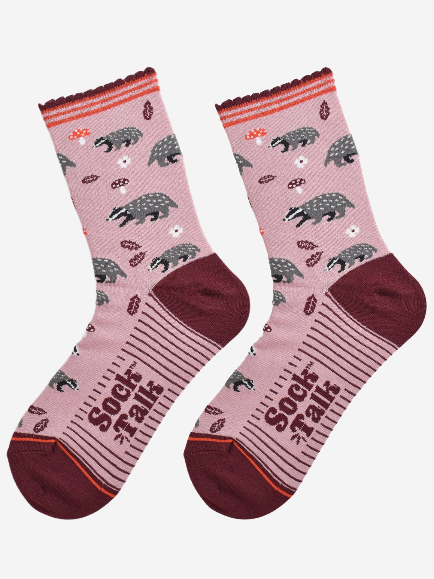 woodland badger bamboo socks laying flat, showing the pattern of badgers, toadstools and autumn leaves on a pink sock with burgundy accents