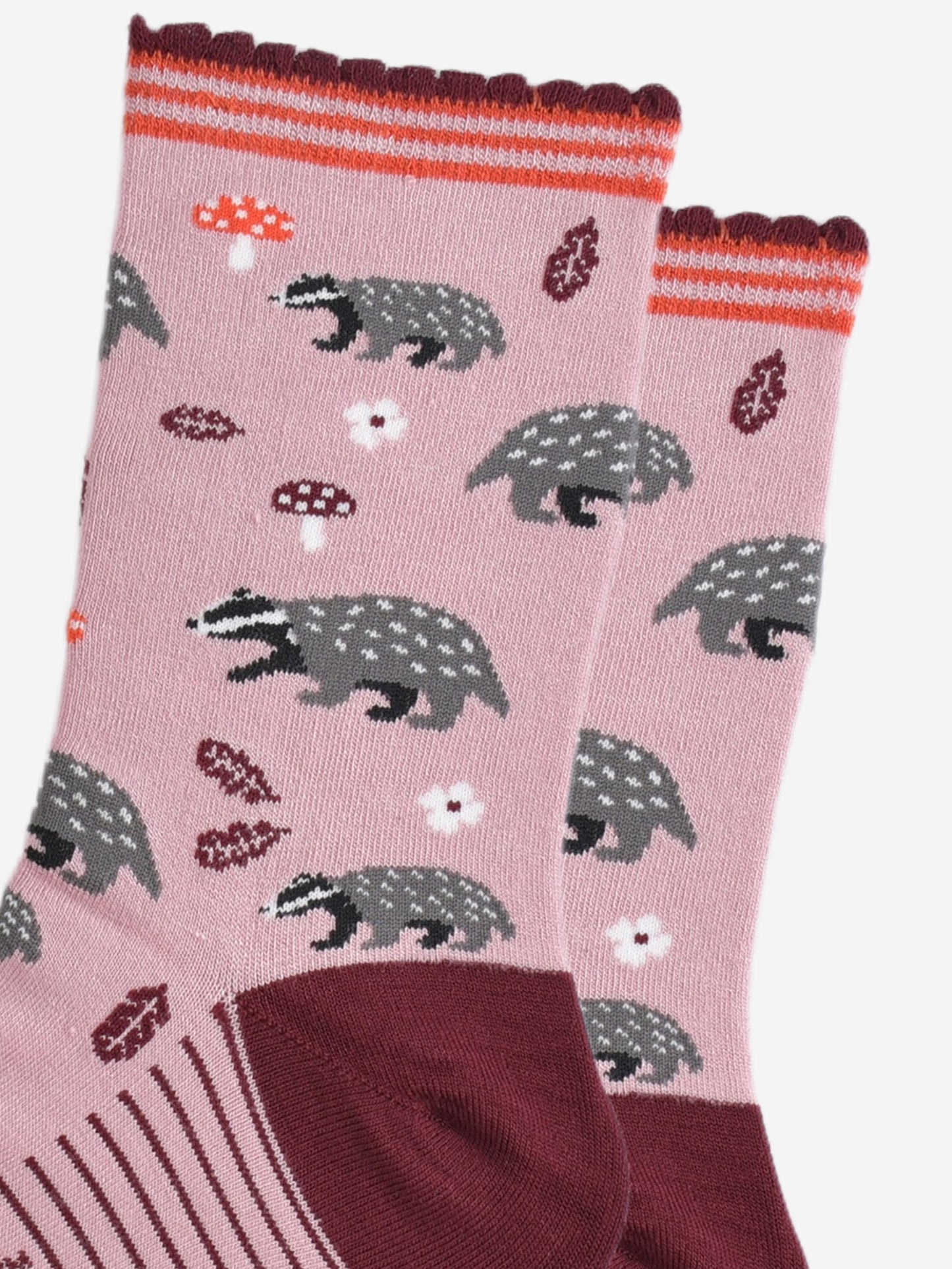 close up of the woodland badger pattern, the socks have grey and black badgers, red toadstools, burgundy red leaves and white flowers on them