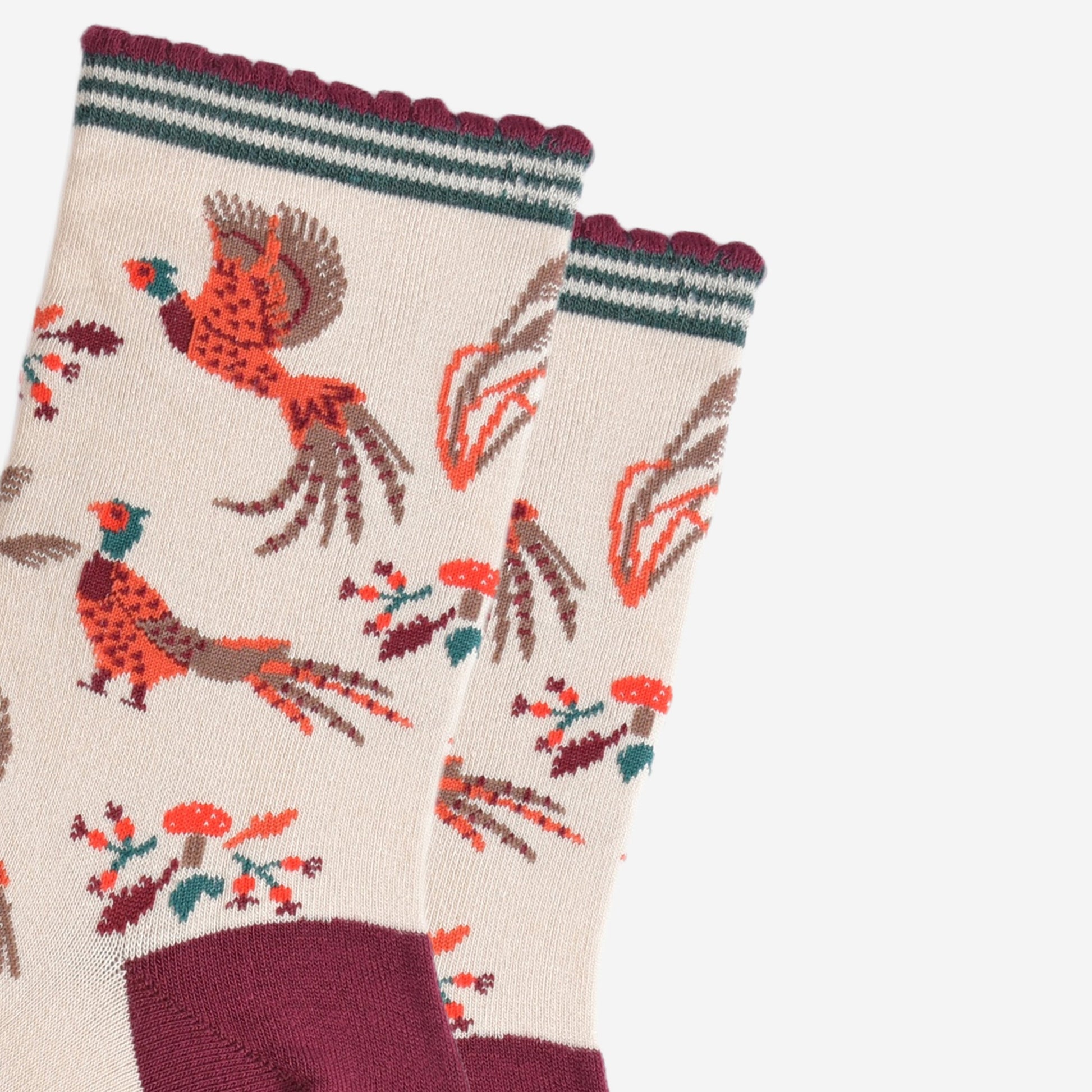 close up of the pheasants, they are illustrated in orange and red and appear to be walking and flying, surrounding the pheasants are autumn leaves and red toadstools