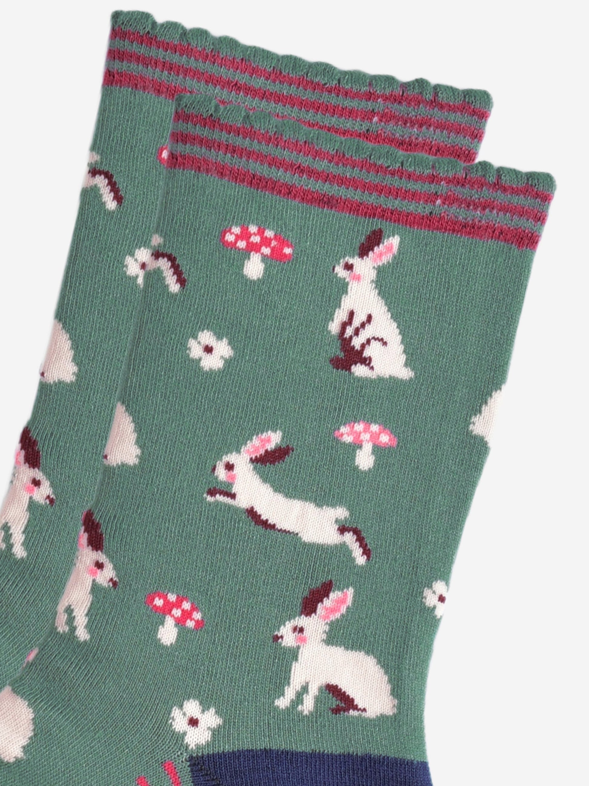 close up of the white rabbit design, the rabbits are sitting, hopping and standing, they have pink rosy cheeks and pink inner ears. there are pink and white toadstools and white flowers scattered around the design.