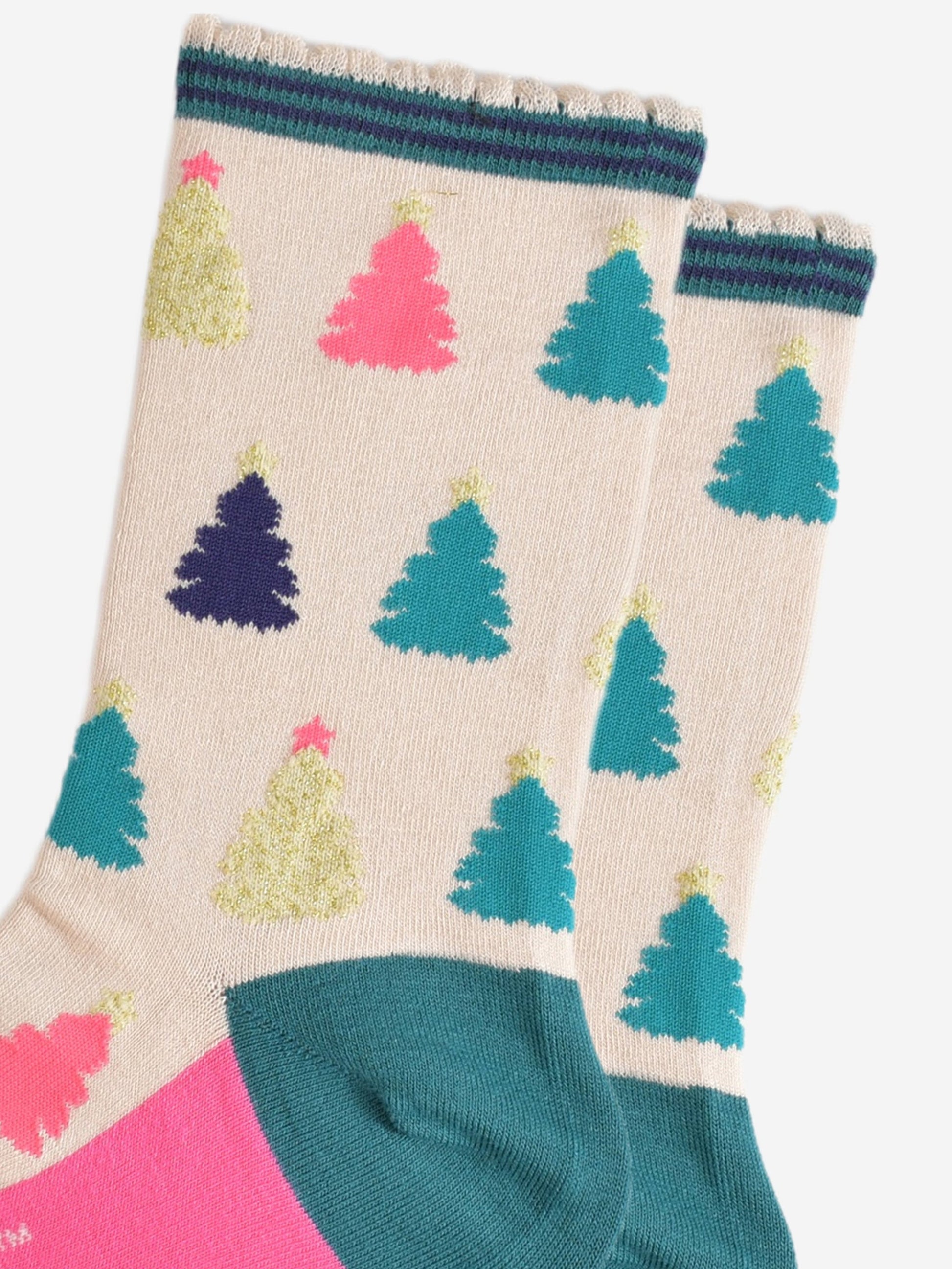 close up of the colourful christmas tree pattern, there are gold, pink, green and blue trees each with stars on the top