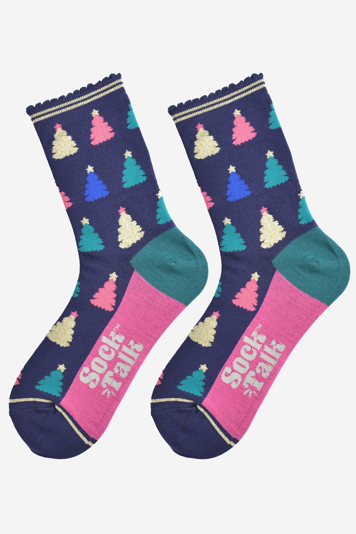 showing the christmas tree socks laying flat, the sole is hot pink in contrast to the navy body of the socks. the xmas tree pattern is all over an in a variety of colours, pink, gold, blue and green