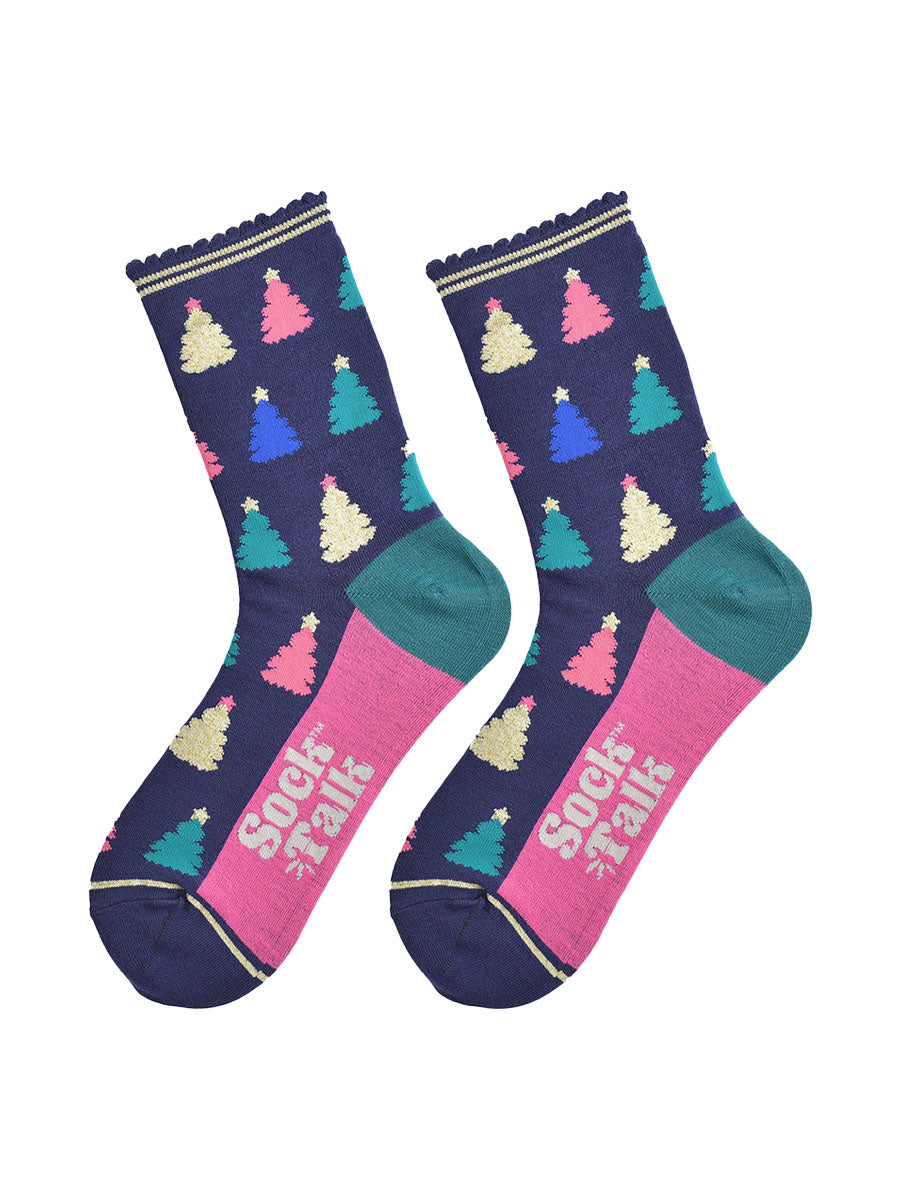showing the christmas tree socks laying flat, the sole is hot pink in contrast to the navy body of the socks. the xmas tree pattern is all over an in a variety of colours, pink, gold, blue and green