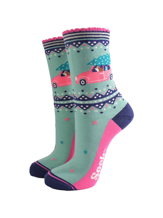 mint green bamboo socks with pink and navy blue accents, on the ankle of the sock there is a hedgehog driving a pink car with a christmas tree on its roof