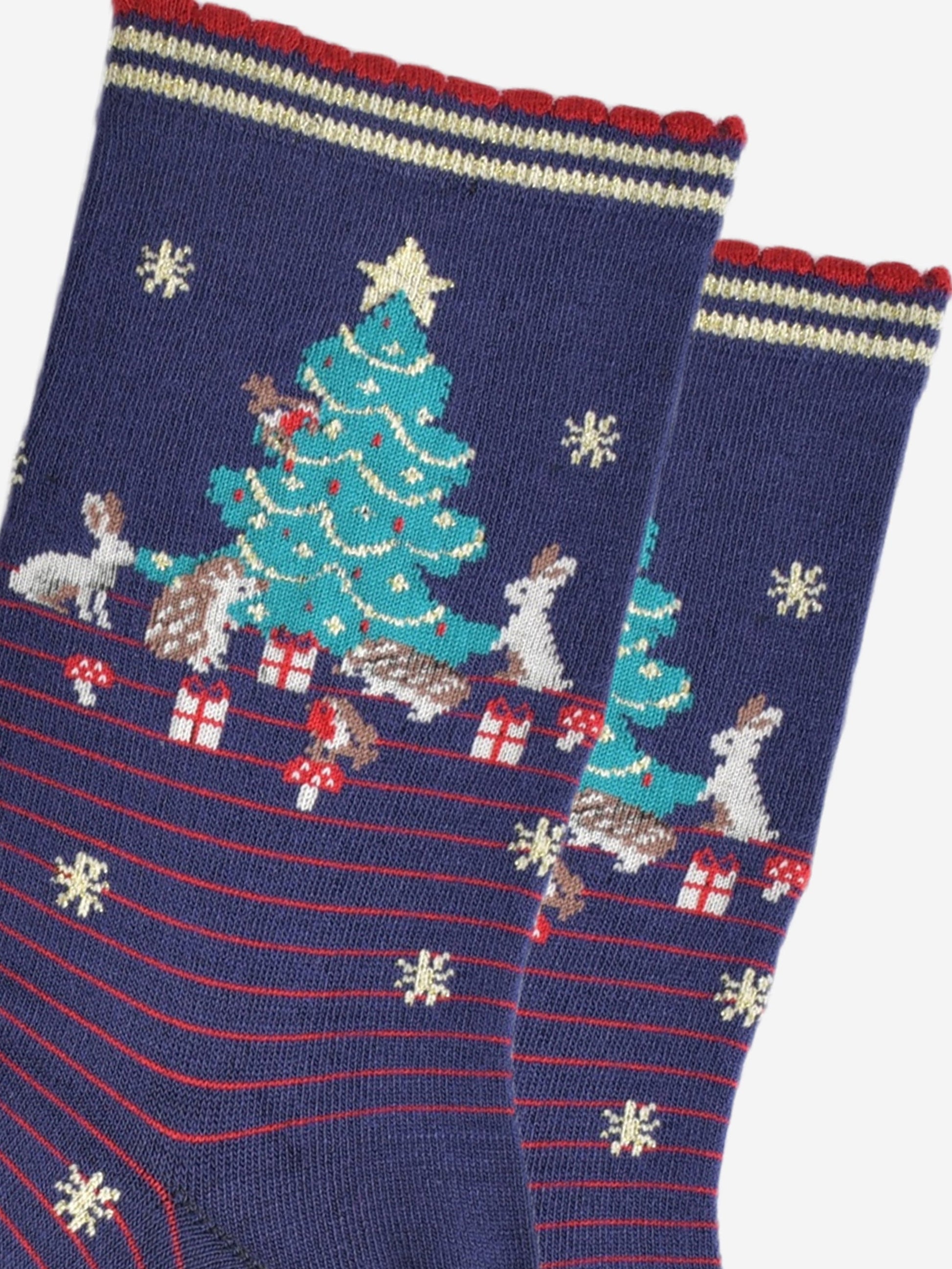 close up of the christmas tree design on the ankle of the socks, there are rabbits, hedgehogs, robins, toadstools and christmas gifts all around the tree