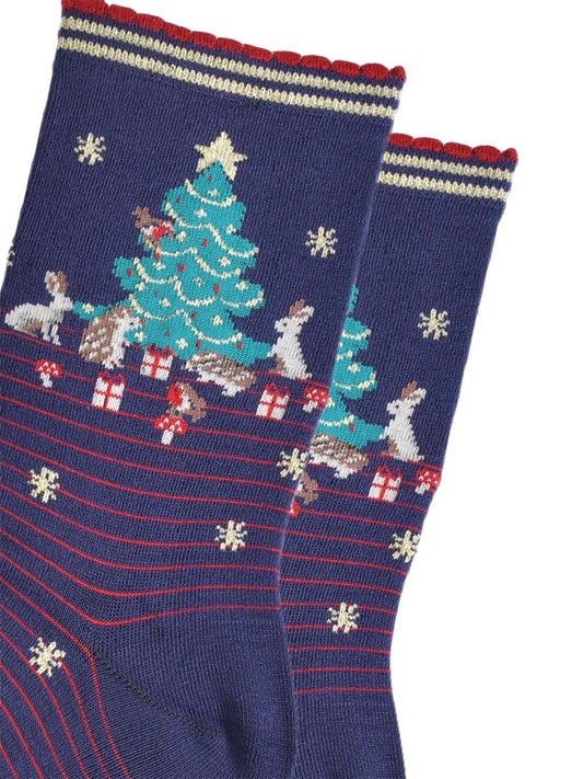 close up of the christmas tree design on the ankle of the socks, there are rabbits, hedgehogs, robins, toadstools and christmas gifts all around the tree
