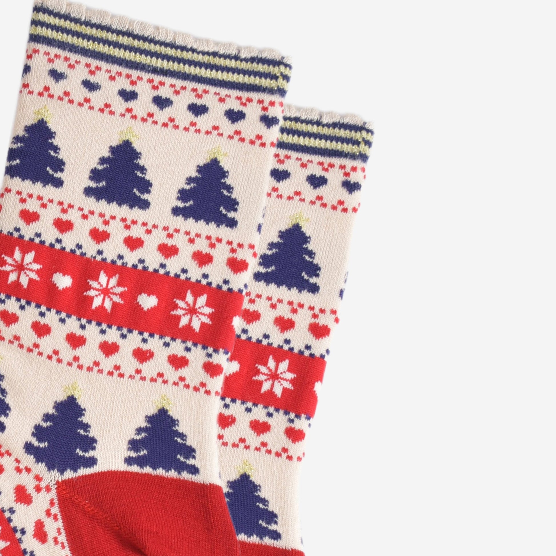 close up of the fair isle pattern on the socks, showing navy blue xmas trees, red love hearts and white snow flakes in a busy fair isle pattern