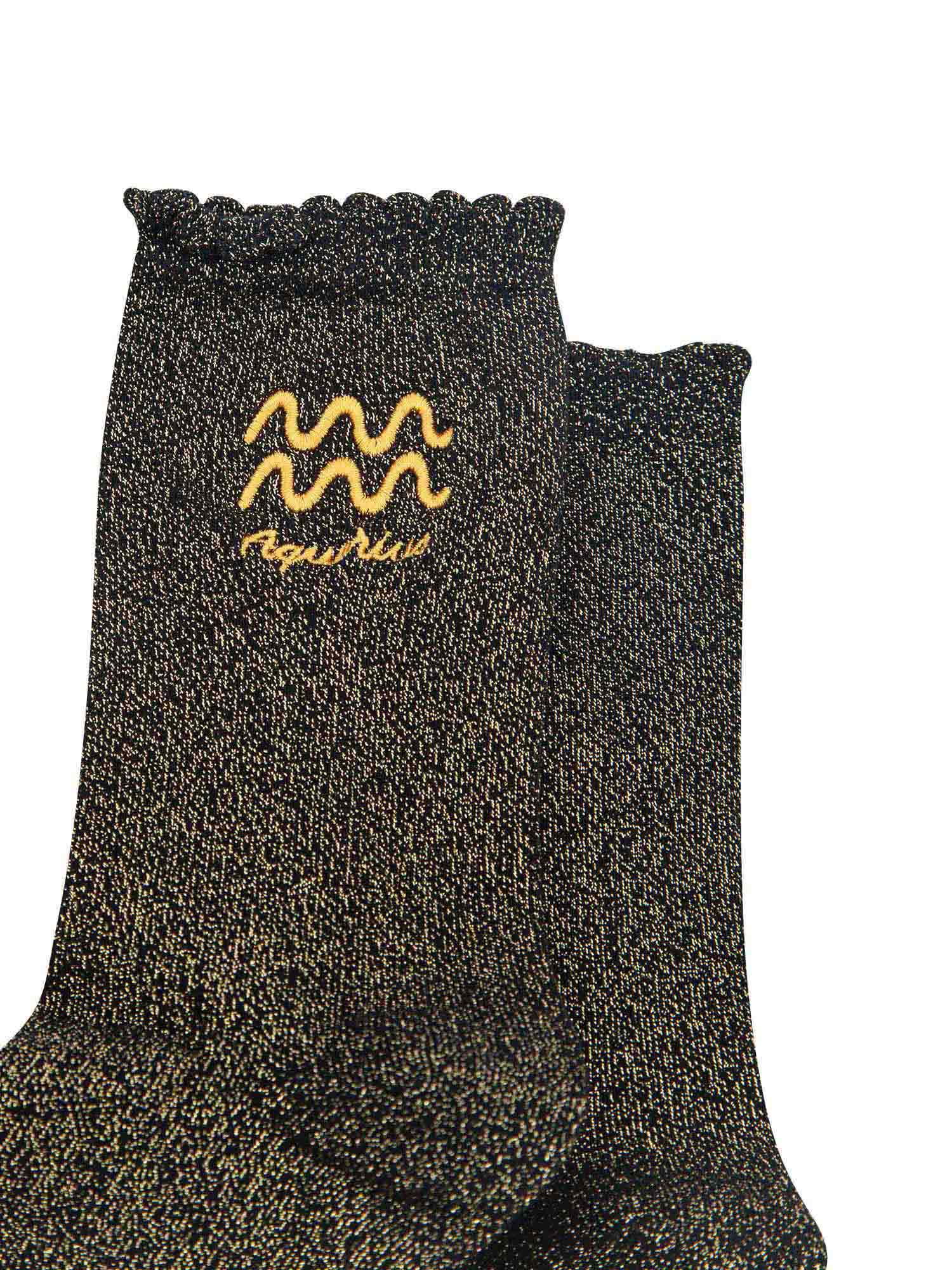close up of the gold embroidered zodiac detail on the ankle of the socks, showing clearly the symbol of and word aquarius

