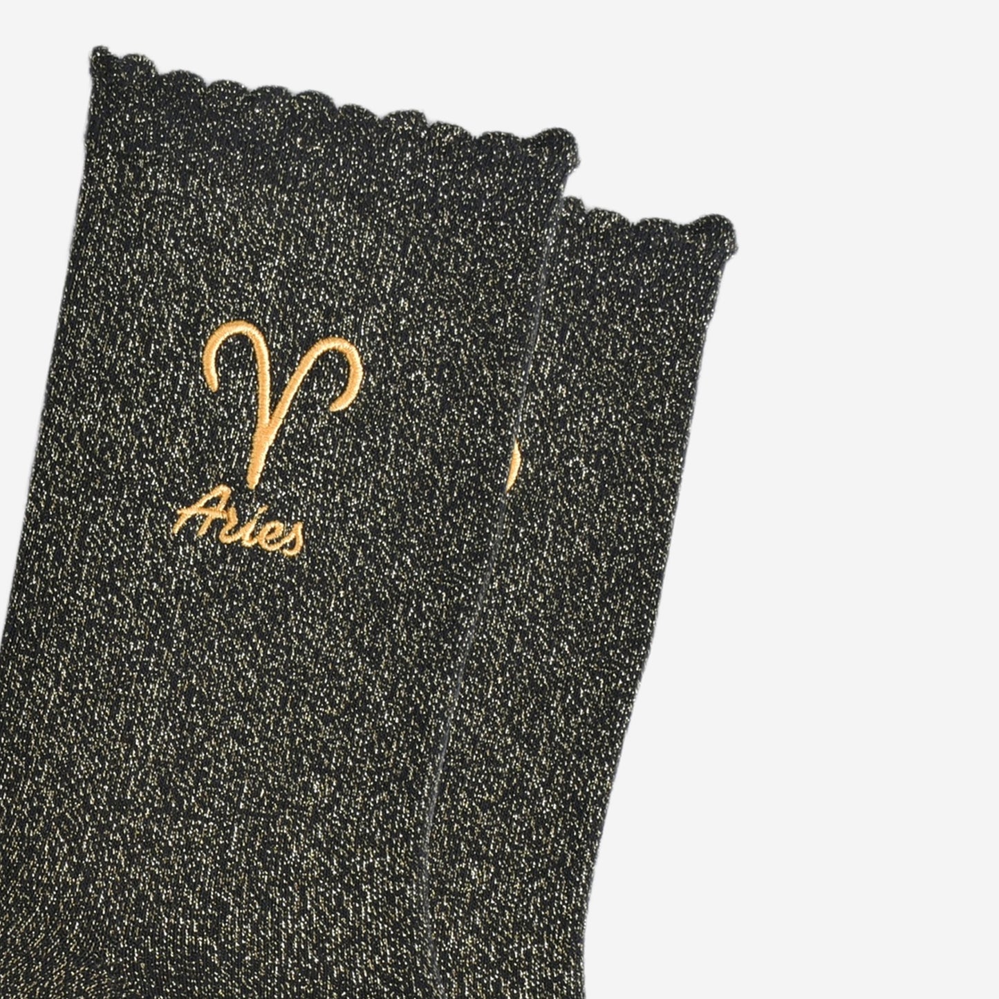 close up of the gold embroidered zodiac detail on the ankle of the socks, showing clearly the symbol of and word aries