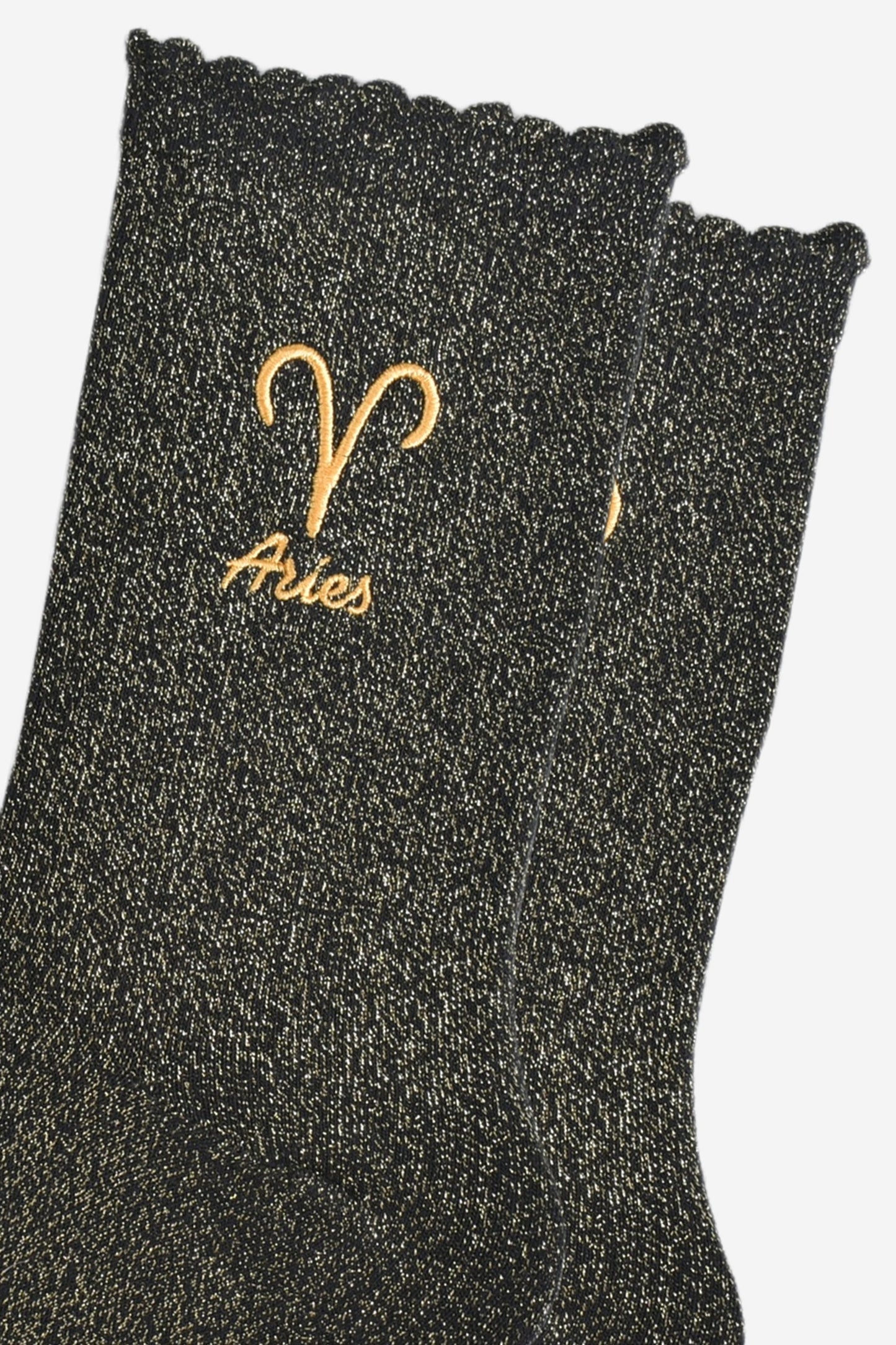 close up of the gold embroidered zodiac detail on the ankle of the socks, showing clearly the symbol of and word aries