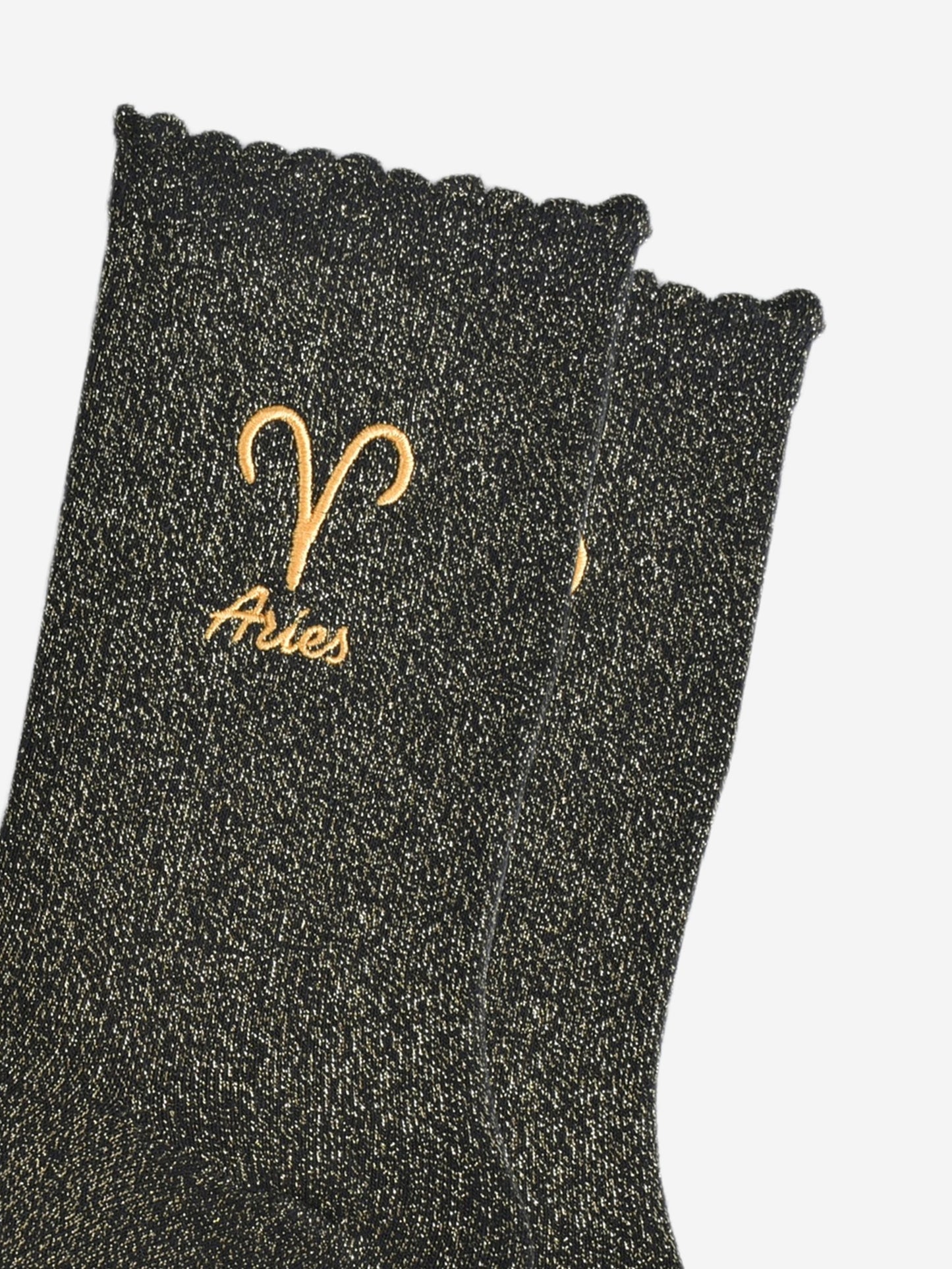 close up of the gold embroidered zodiac detail on the ankle of the socks, showing clearly the symbol of and word aries