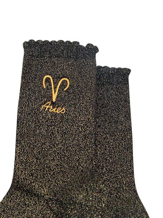 close up of the gold embroidered zodiac detail on the ankle of the socks, showing clearly the symbol of and word aries