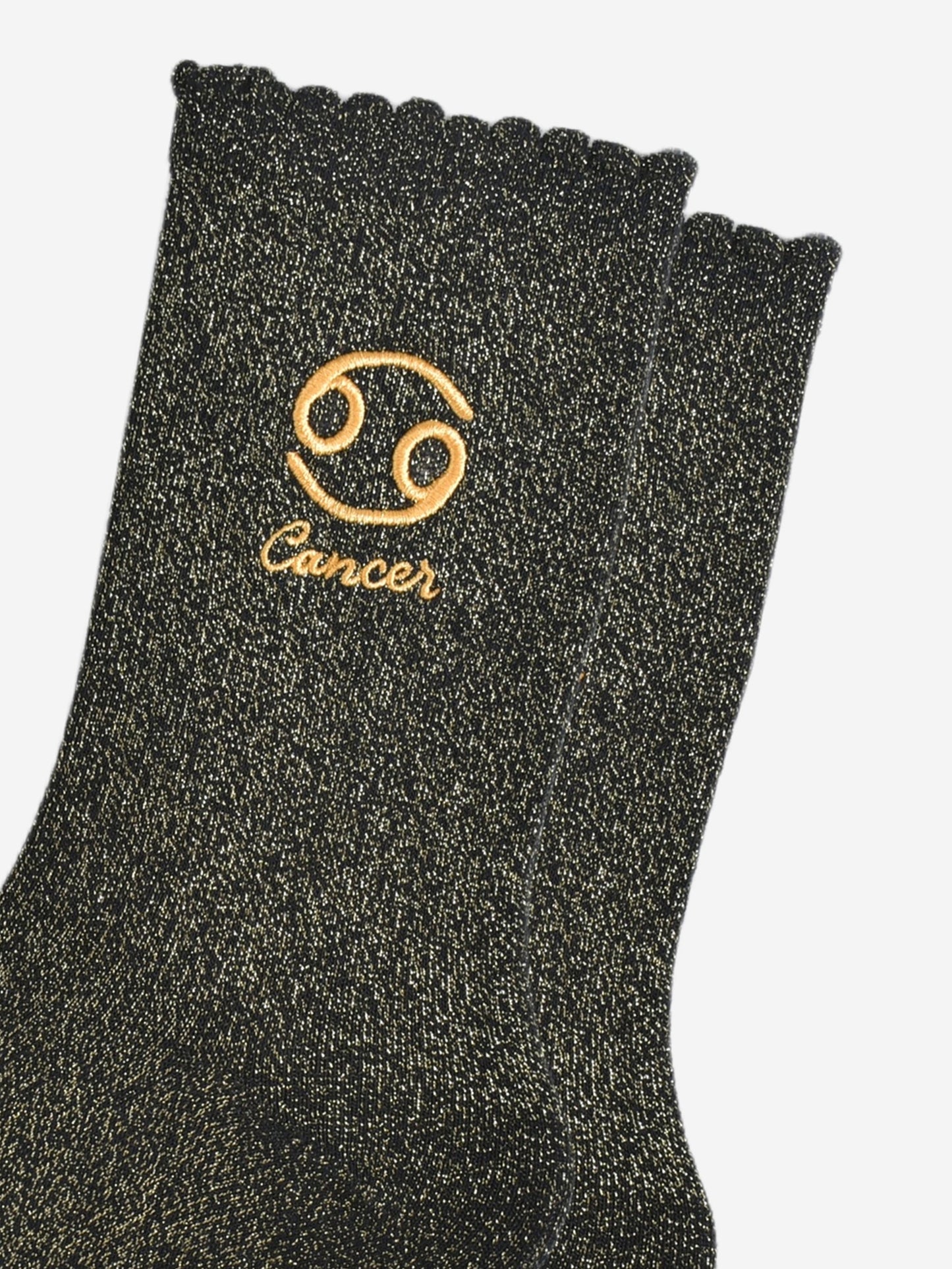 close up of the gold embroidered zodiac detail on the ankle of the socks, showing clearly the symbol of and word cancer