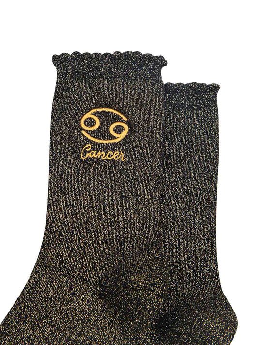 close up of the gold embroidered zodiac detail on the ankle of the socks, showing clearly the symbol of and word cancer