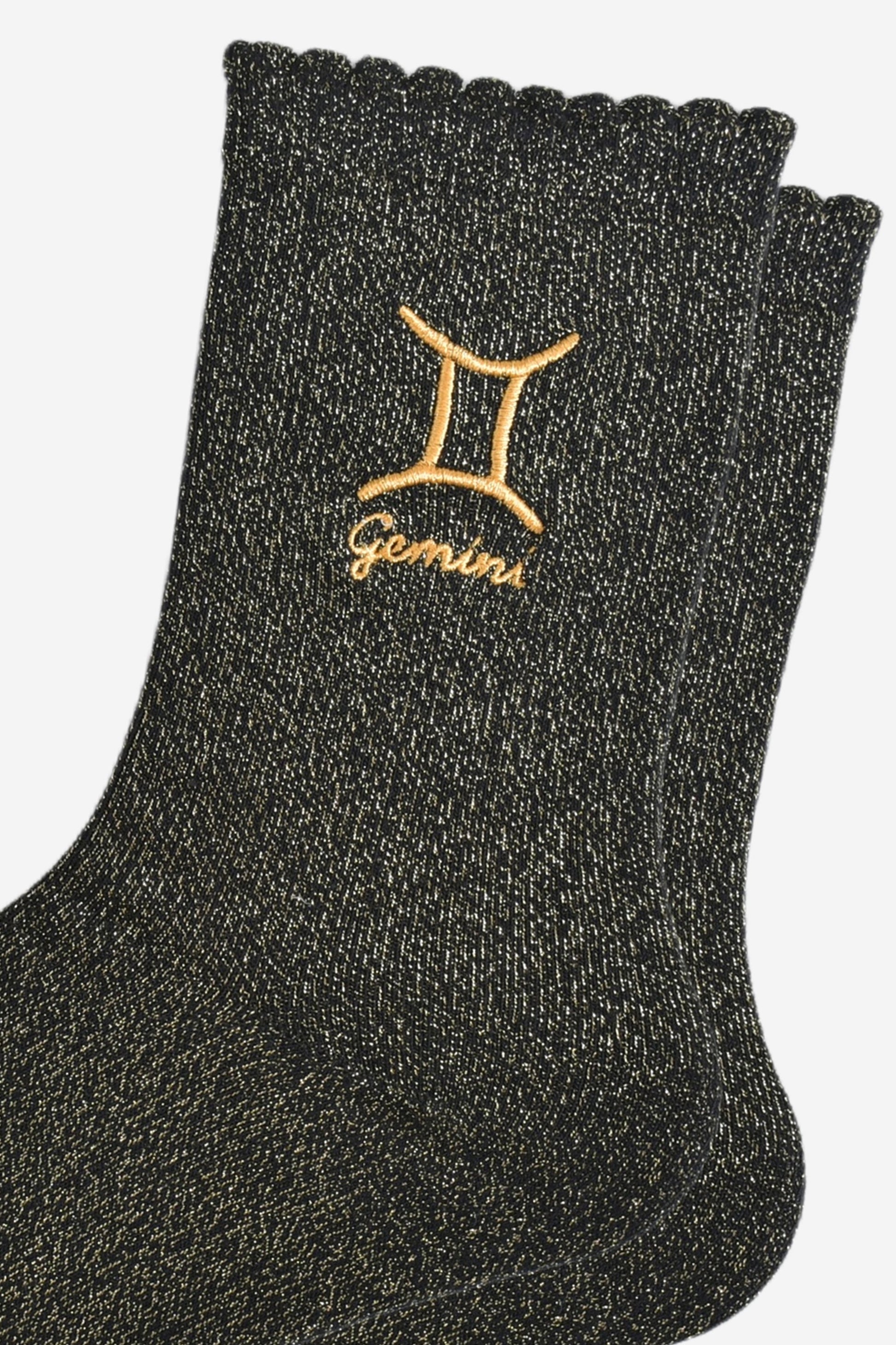 close up of the gold embroidered zodiac detail on the ankle of the socks, showing clearly the symbol of and word gemini