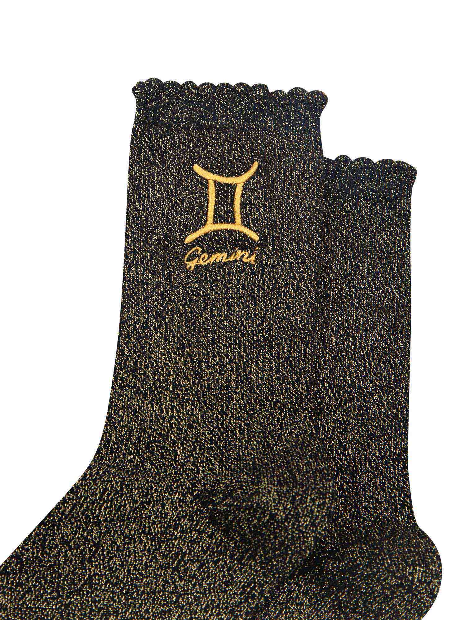 close up of the gold embroidered zodiac detail on the ankle of the socks, showing clearly the symbol of and word gemini