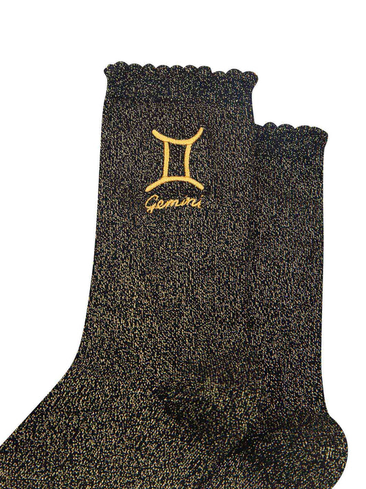 close up of the gold embroidered zodiac detail on the ankle of the socks, showing clearly the symbol of and word gemini