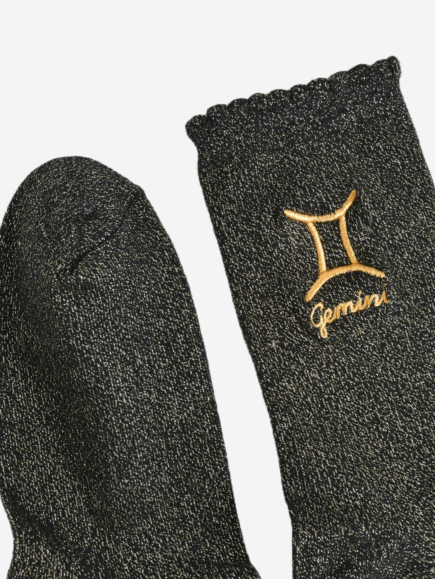 showing the toe and cuff of the socks, they are the same black and gold sparkly colour as the body of the socks, the cuff is scalloped shaped like a slight frill