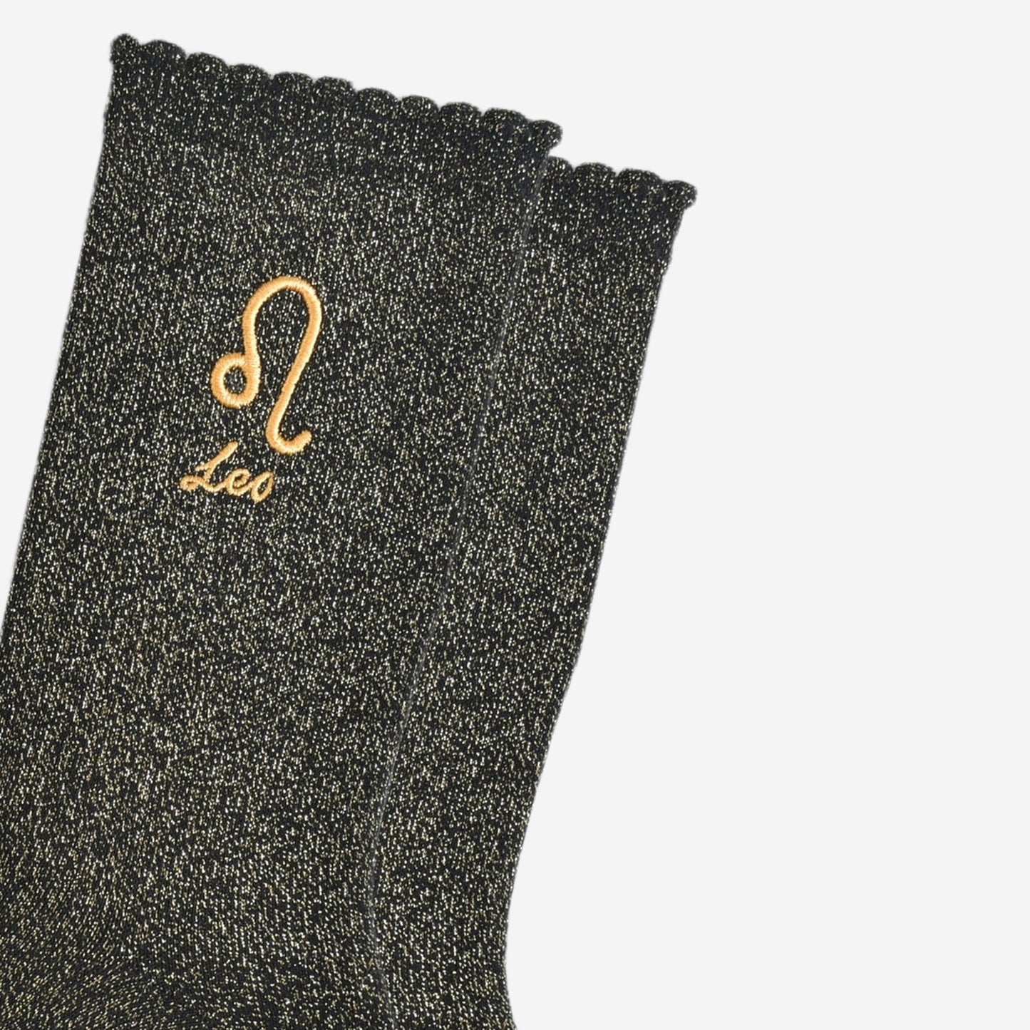 close up of the gold embroidered zodiac detail on the ankle of the socks, showing clearly the symbol of and word leo