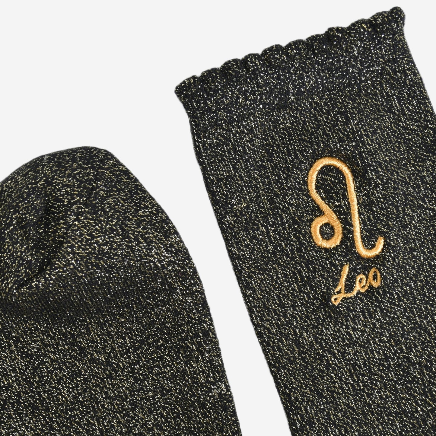 showing the toe and cuff of the socks, they are the same black and gold sparkly colour as the body of the socks, the cuff is scalloped shaped like a slight frill