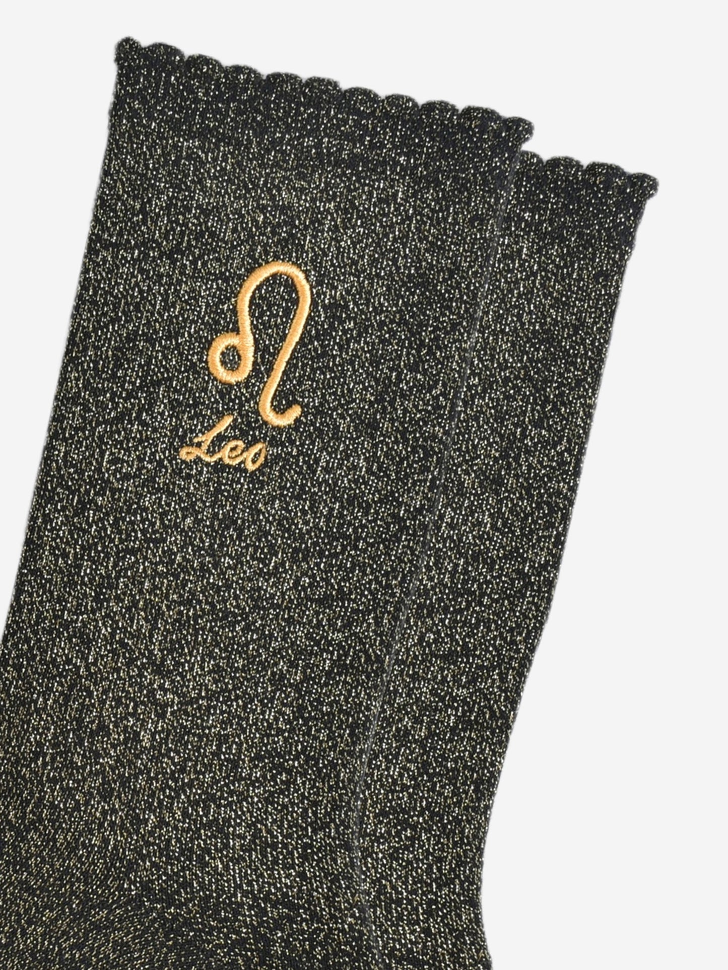 close up of the gold embroidered zodiac detail on the ankle of the socks, showing clearly the symbol of and word leo