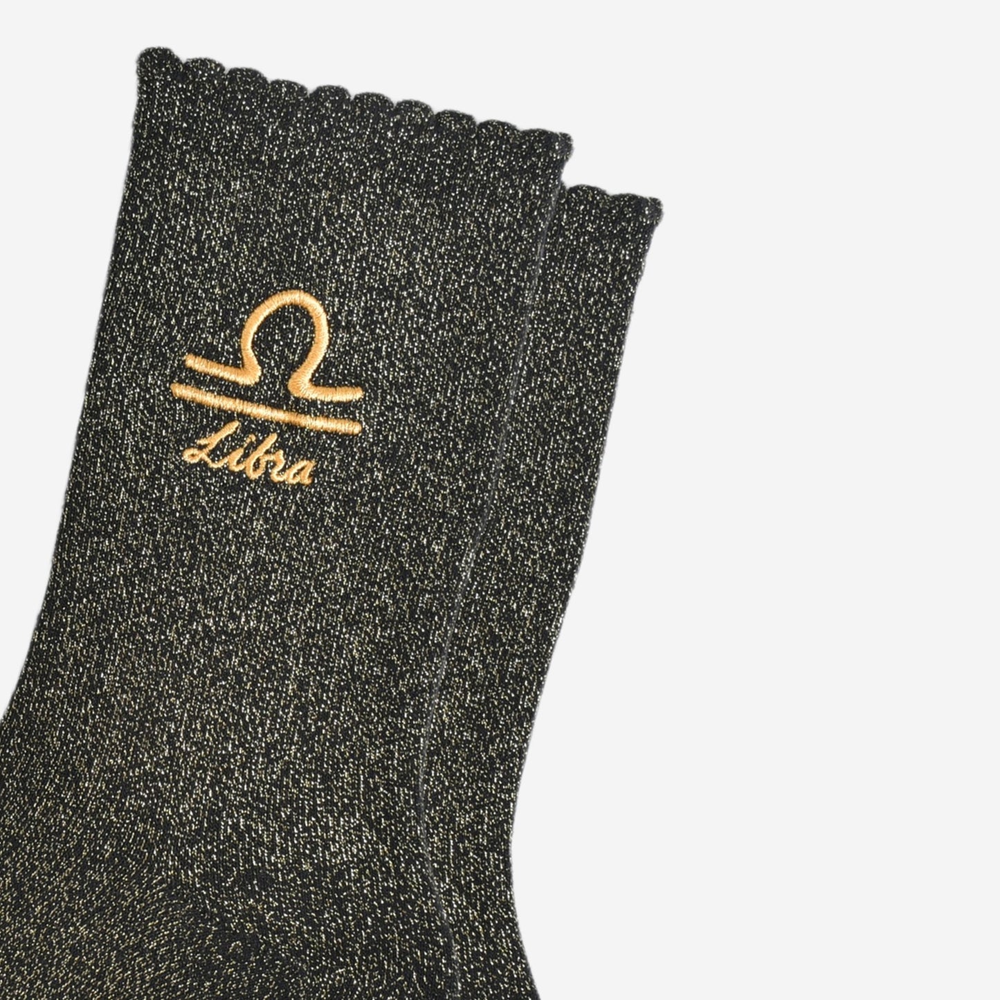 close up of the gold embroidered zodiac detail on the ankle of the socks, showing clearly the symbol of and word libra