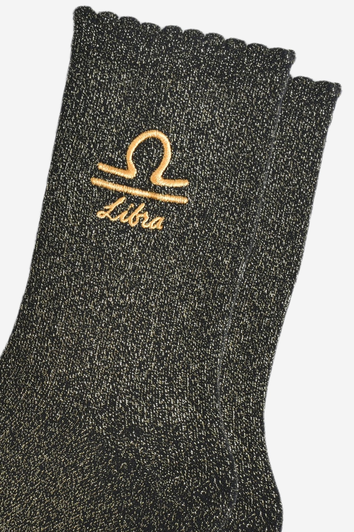 close up of the gold embroidered zodiac detail on the ankle of the socks, showing clearly the symbol of and word libra