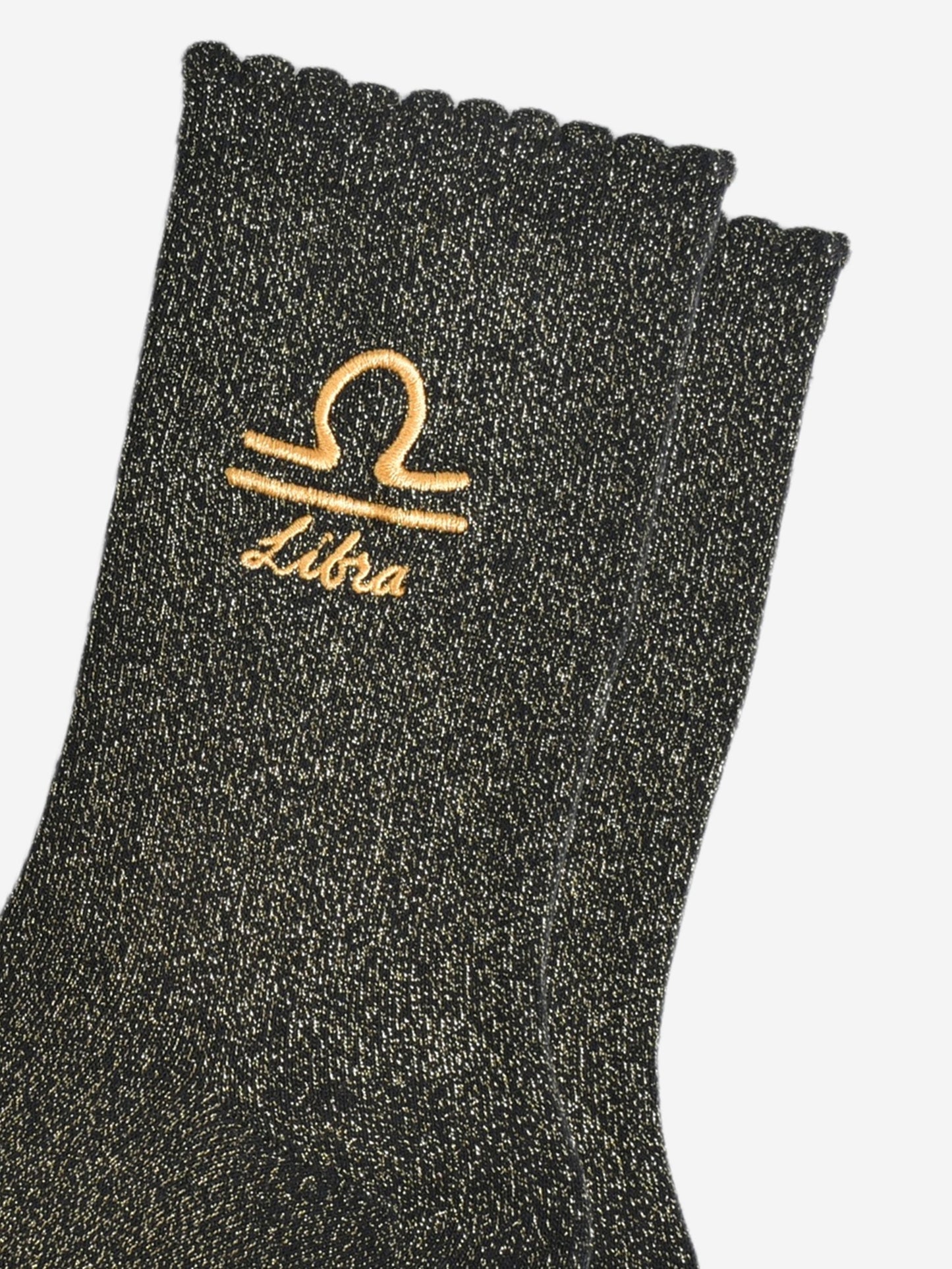 close up of the gold embroidered zodiac detail on the ankle of the socks, showing clearly the symbol of and word libra