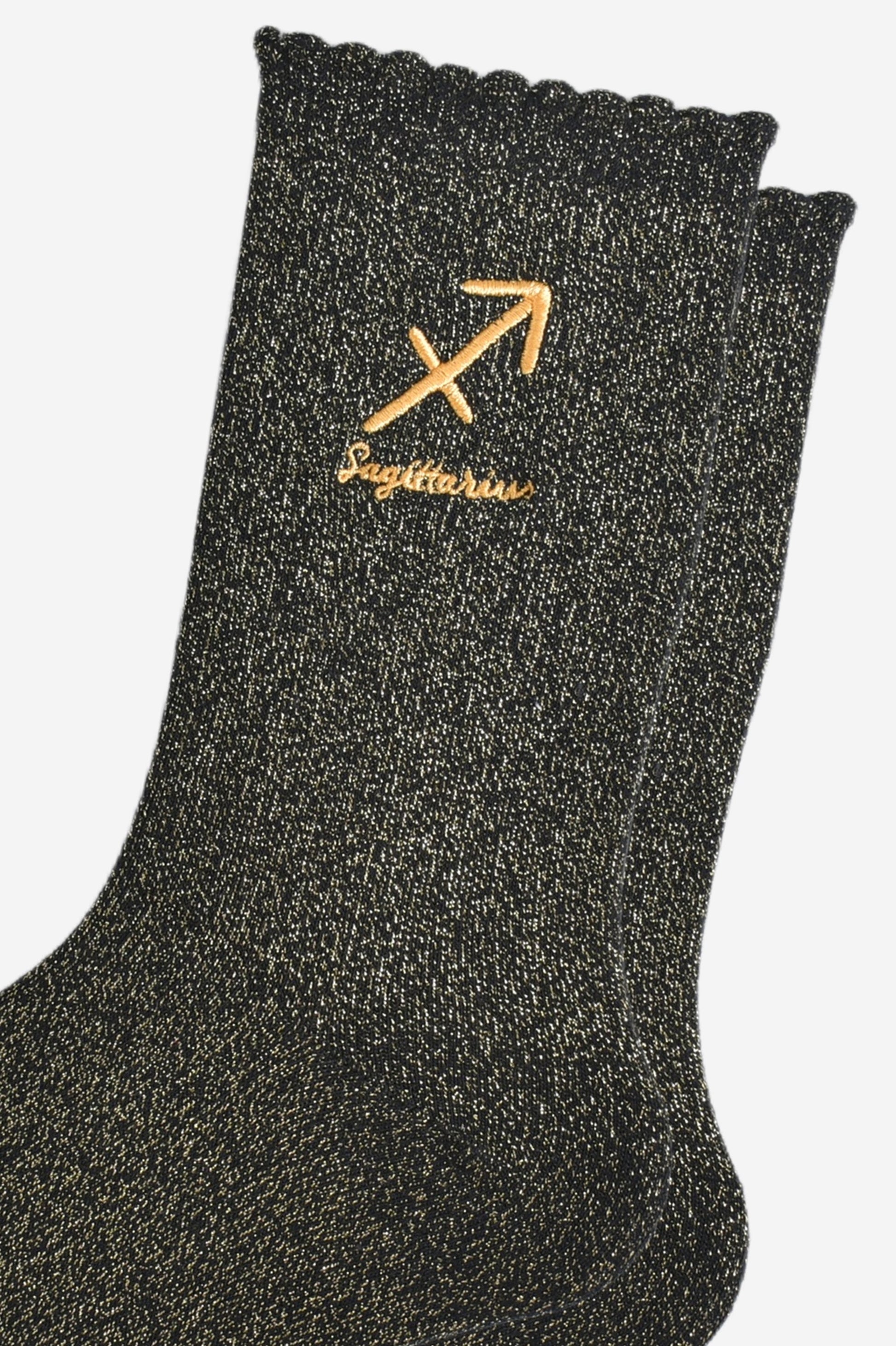 close up of the gold embroidered zodiac detail on the ankle of the socks, showing clearly the symbol of and word sagittarius