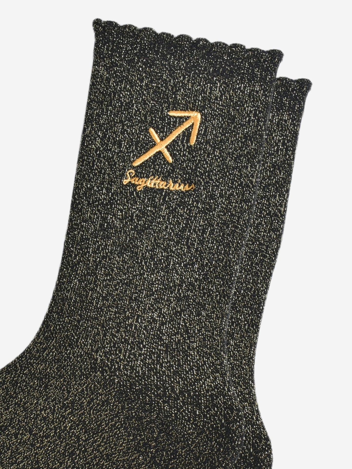 close up of the gold embroidered zodiac detail on the ankle of the socks, showing clearly the symbol of and word sagittarius