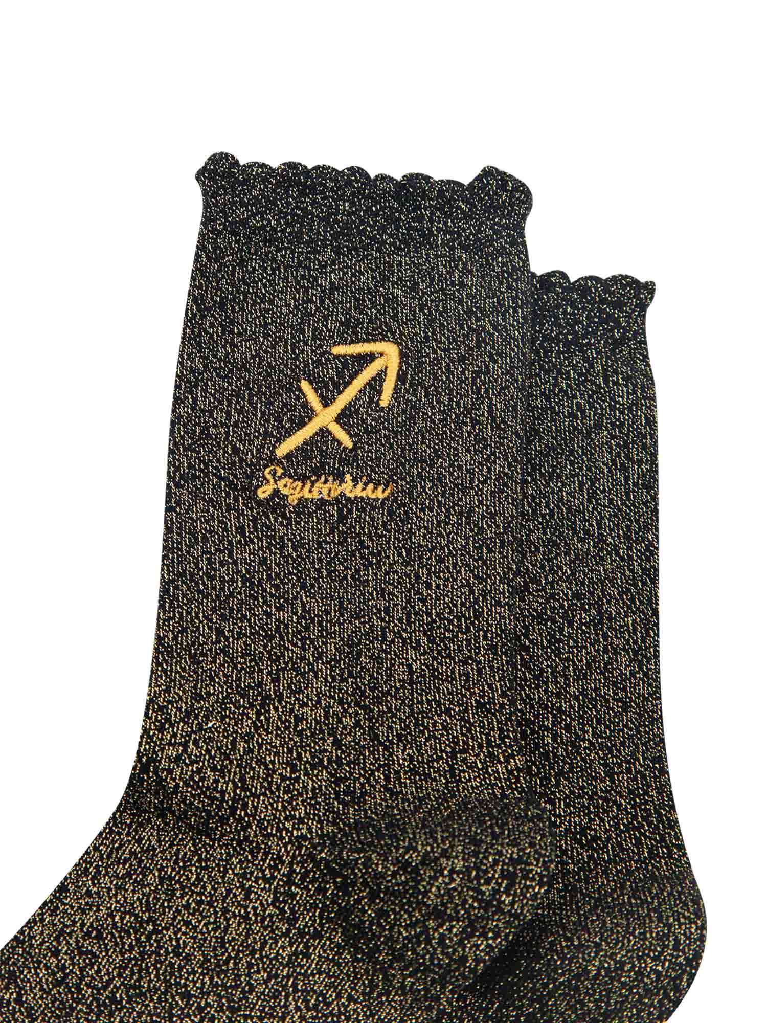 close up of the gold embroidered zodiac detail on the ankle of the socks, showing clearly the symbol of and word sagittarius
