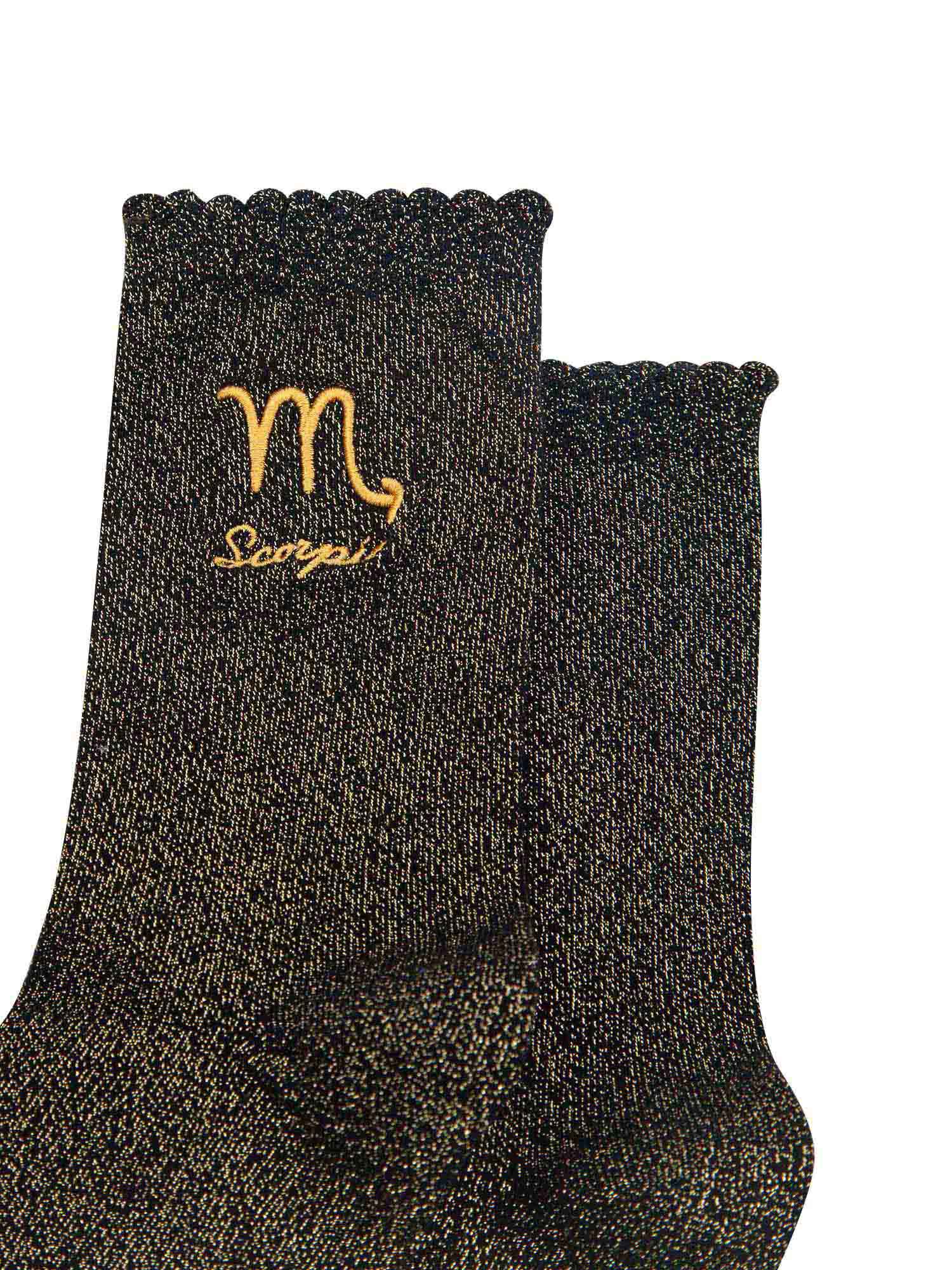 close up of the gold embroidered zodiac detail on the ankle of the socks, showing clearly the symbol of and word scorpio