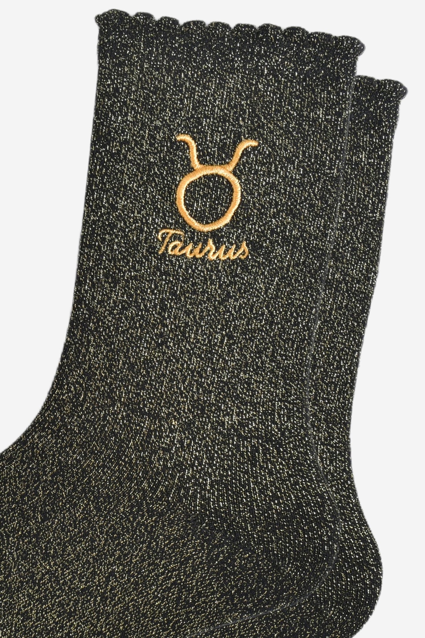 close up of the gold embroidered zodiac detail on the ankle of the socks, showing clearly the symbol of and word taurus