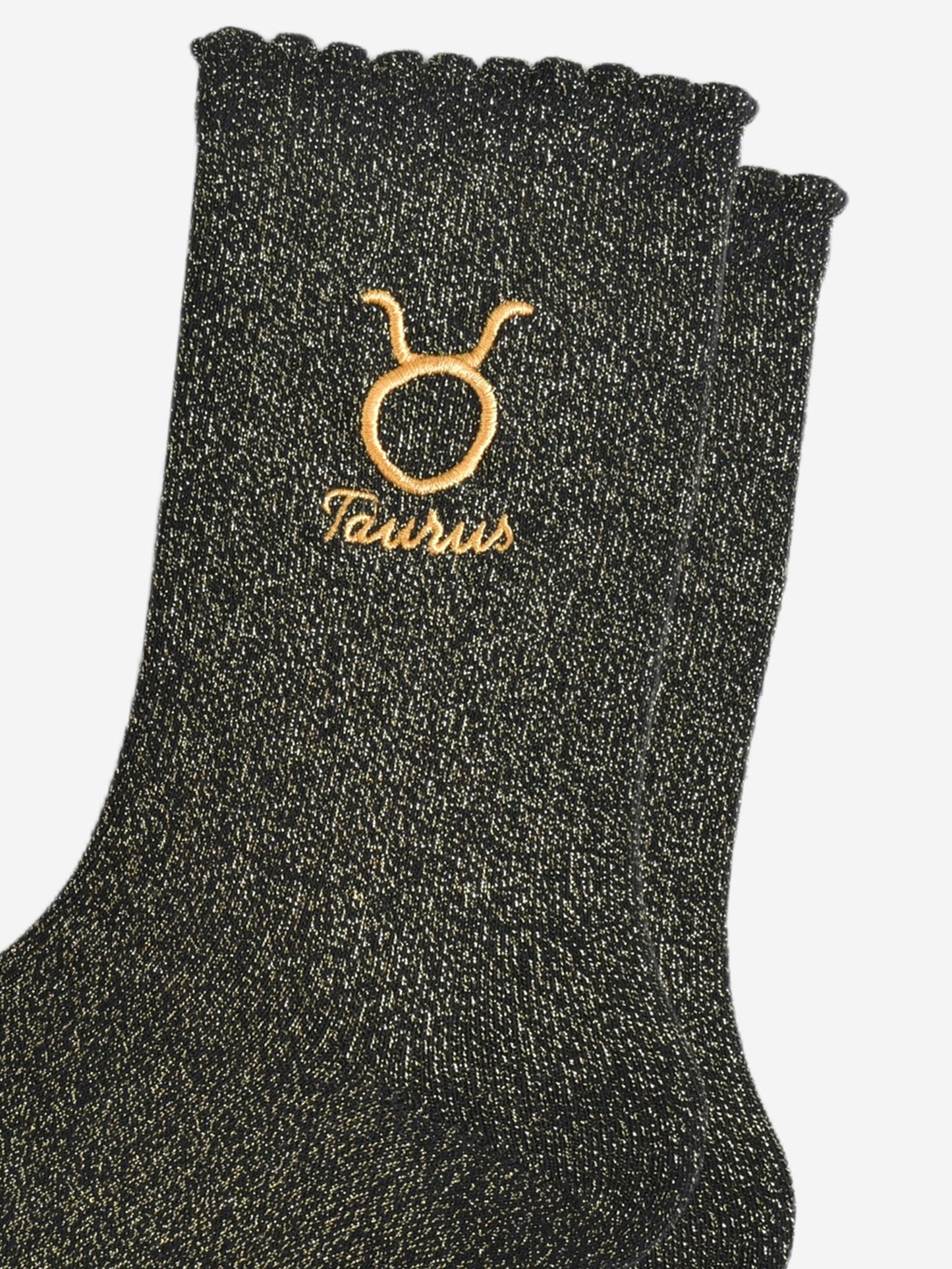 close up of the gold embroidered zodiac detail on the ankle of the socks, showing clearly the symbol of and word taurus