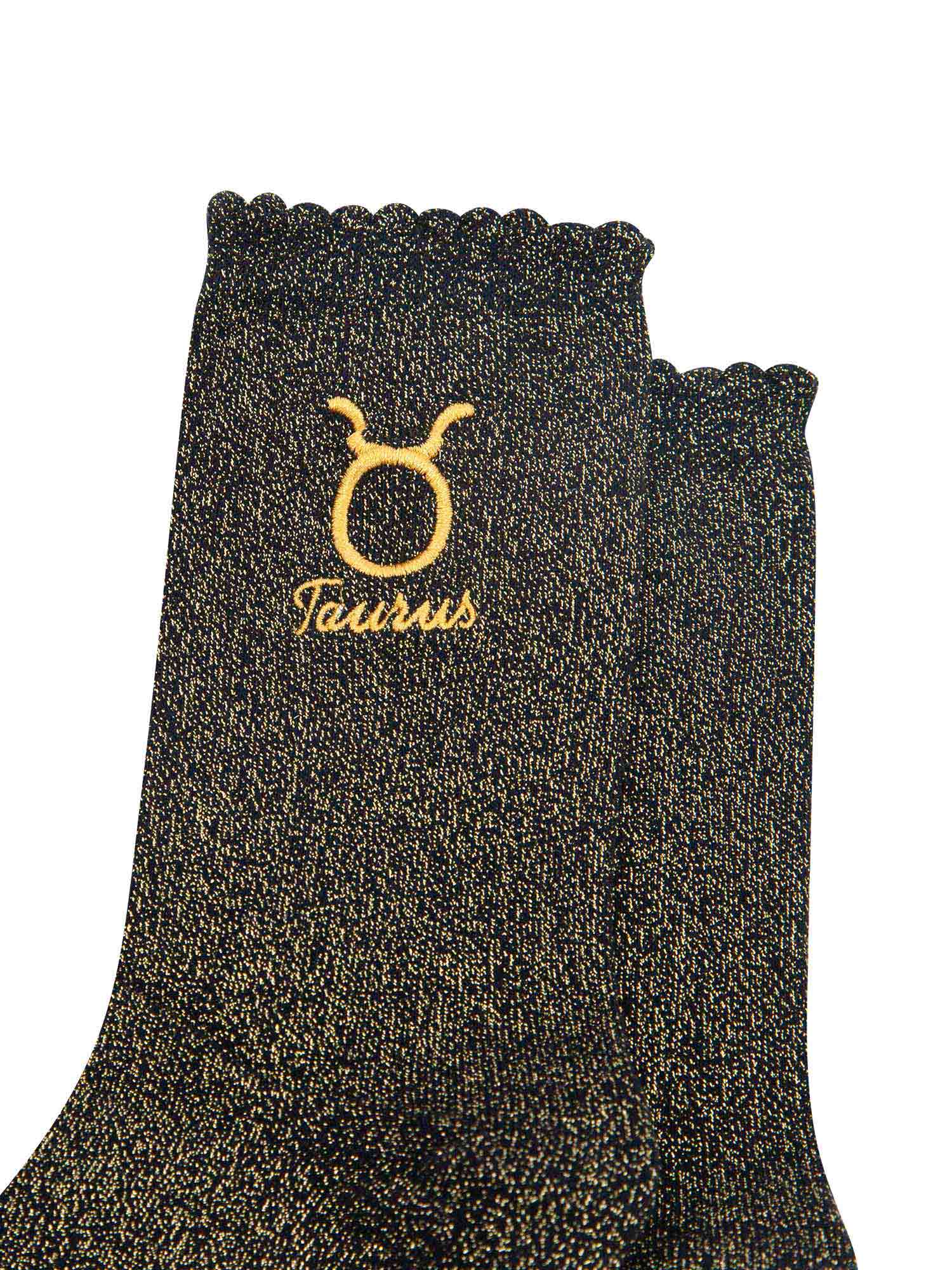 close up of the gold embroidered zodiac detail on the ankle of the socks, showing clearly the symbol of and word taurus