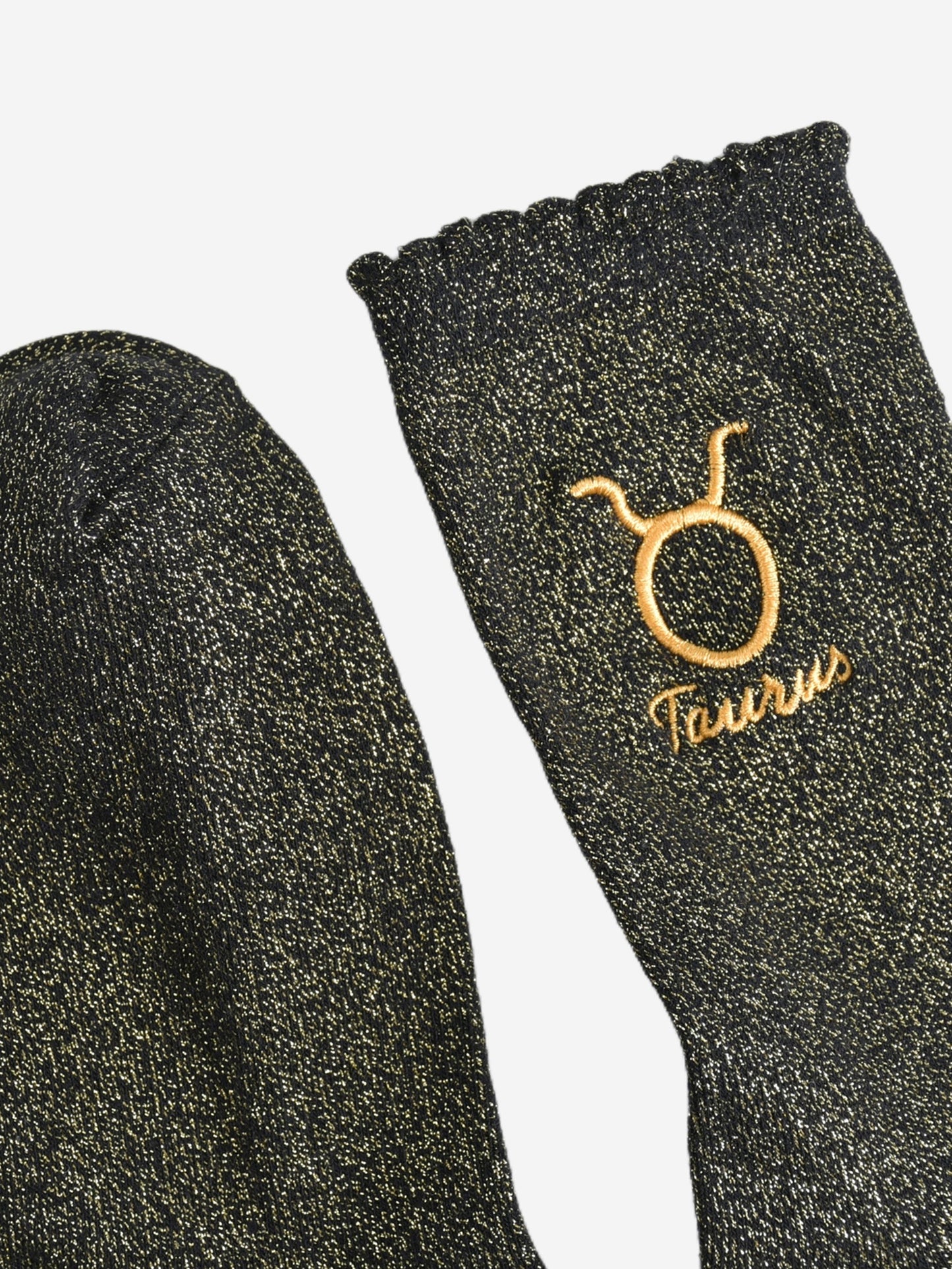 showing the toe and cuff of the socks, they are the same black and gold sparkly colour as the body of the socks, the cuff is scalloped shaped like a slight frill