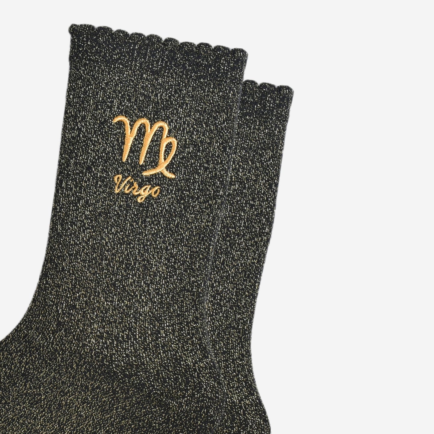 close up of the gold embroidered zodiac detail on the ankle of the socks, showing clearly the symbol of and word virgo