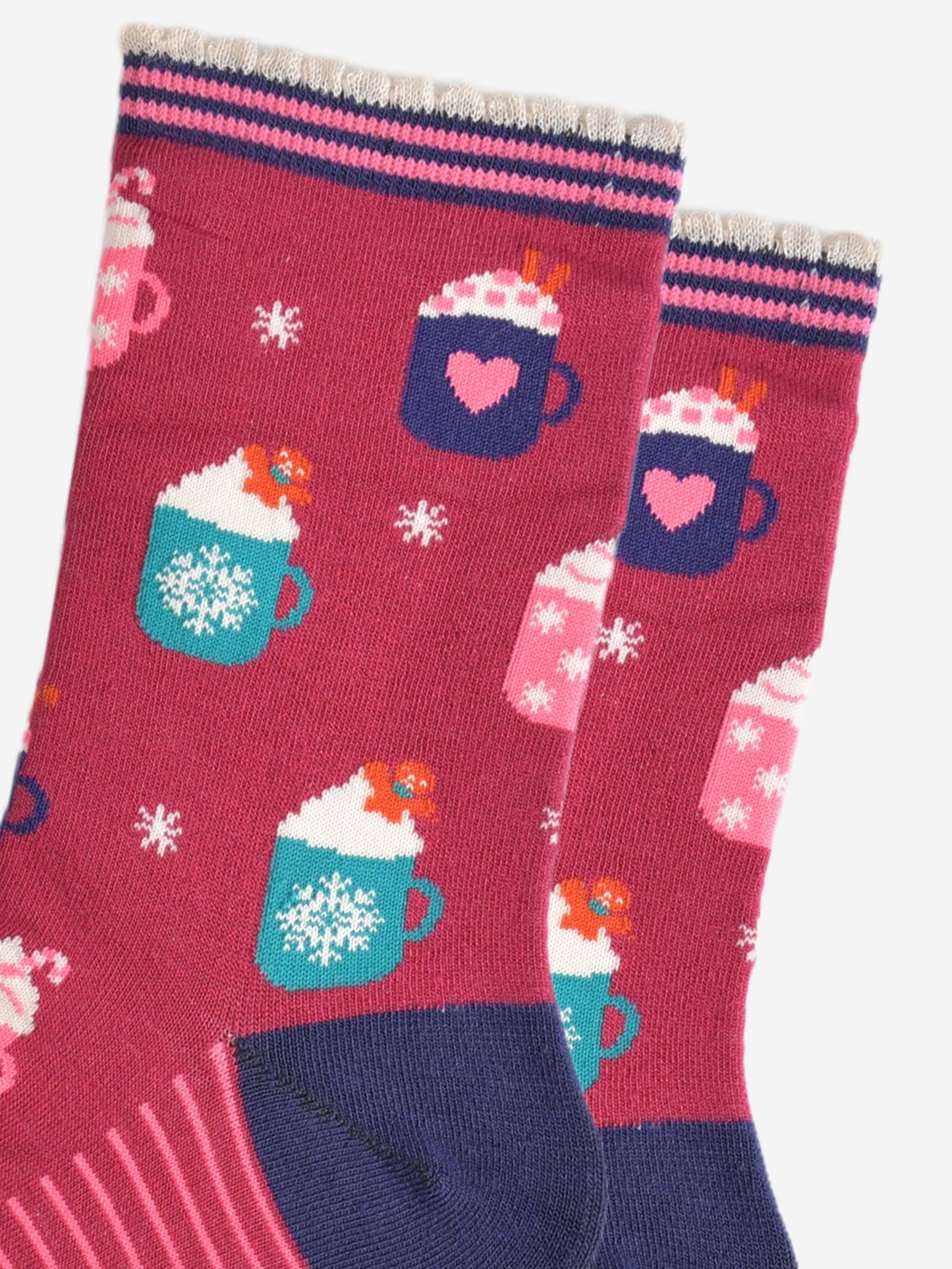 close up of the hot drinks design on the socks, there are teal coloured mugs with a white snowflake pattern topped with whipped creme and a gingerbread man cookie, there are pink mugs with pink candy canes and navy mugs with pink love hearts with pink sugar hearts and cinnamon sticks.