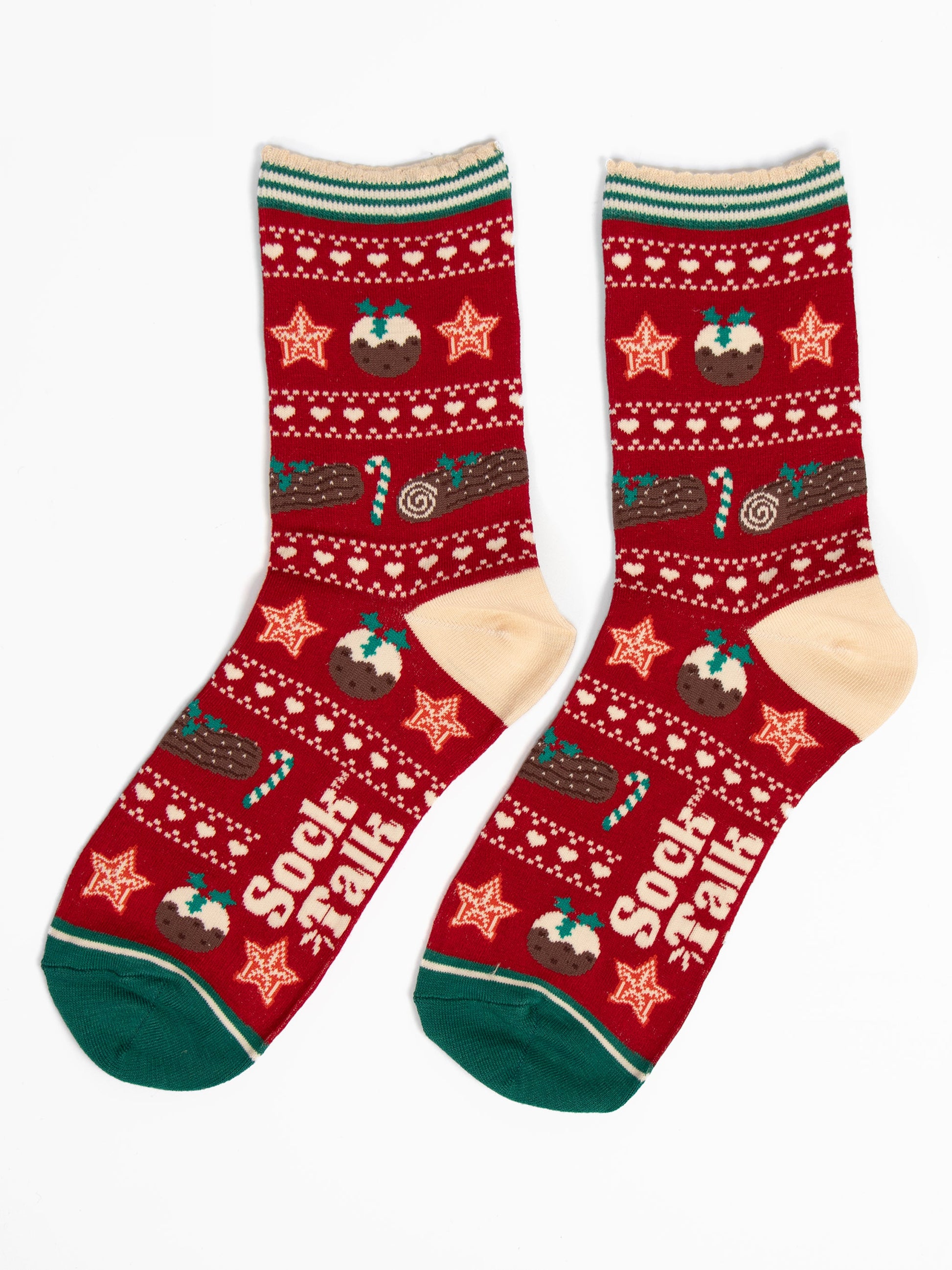 showing the christmas pudding fair isle socks laying flat. the christmas treats are in rows, separated by white dots and love hearts. The socks have a cream heel and green toe in contrast to the red background of the socks.