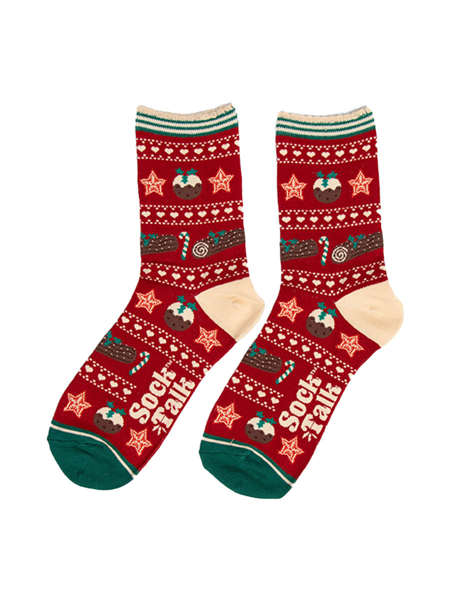 showing the christmas pudding fair isle socks laying flat. the christmas treats are in rows, separated by white dots and love hearts. The socks have a cream heel and green toe in contrast to the red background of the socks.