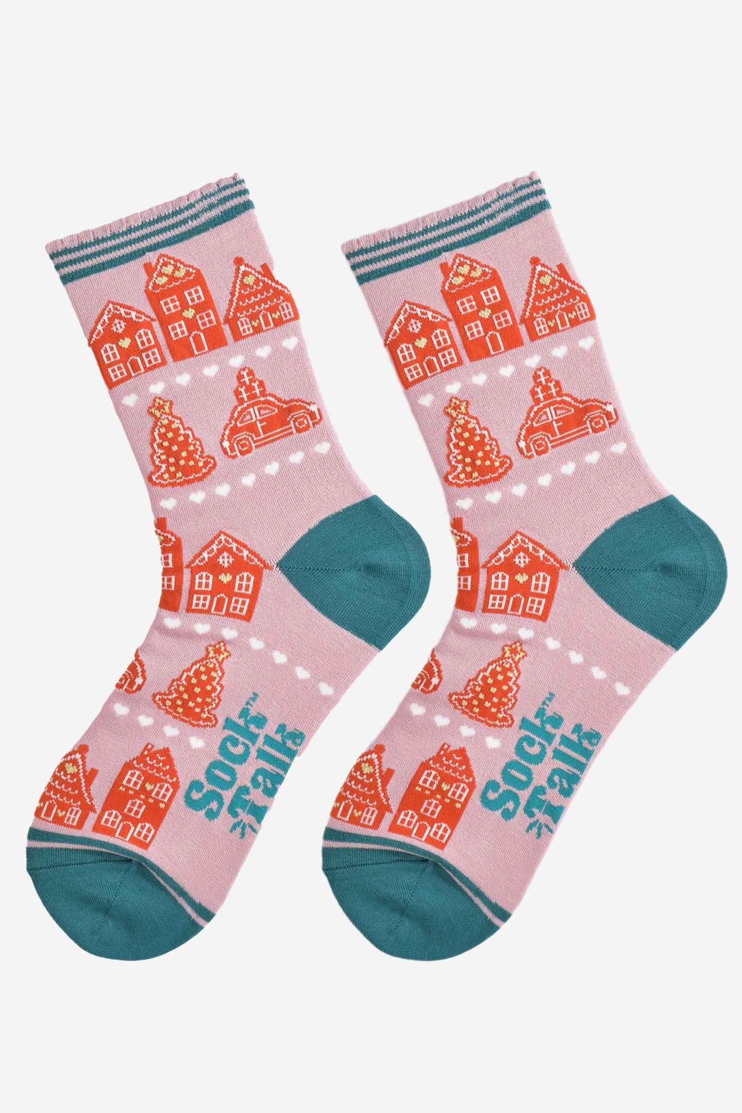 showing the gingerbread house socks laying flat, the pattern is in rows separated by white love heats, the toe and heel of the socks are teal blue in contrast to the light pink background.