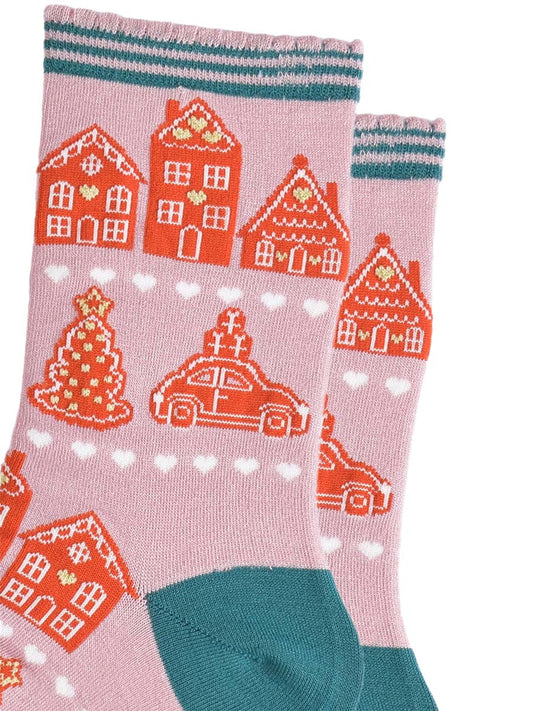 close up of the gingerbread cookie design, they are shaped like houses, christmas trees and cars. the gingerbread cookies are orange with white icing and gold love heart details.